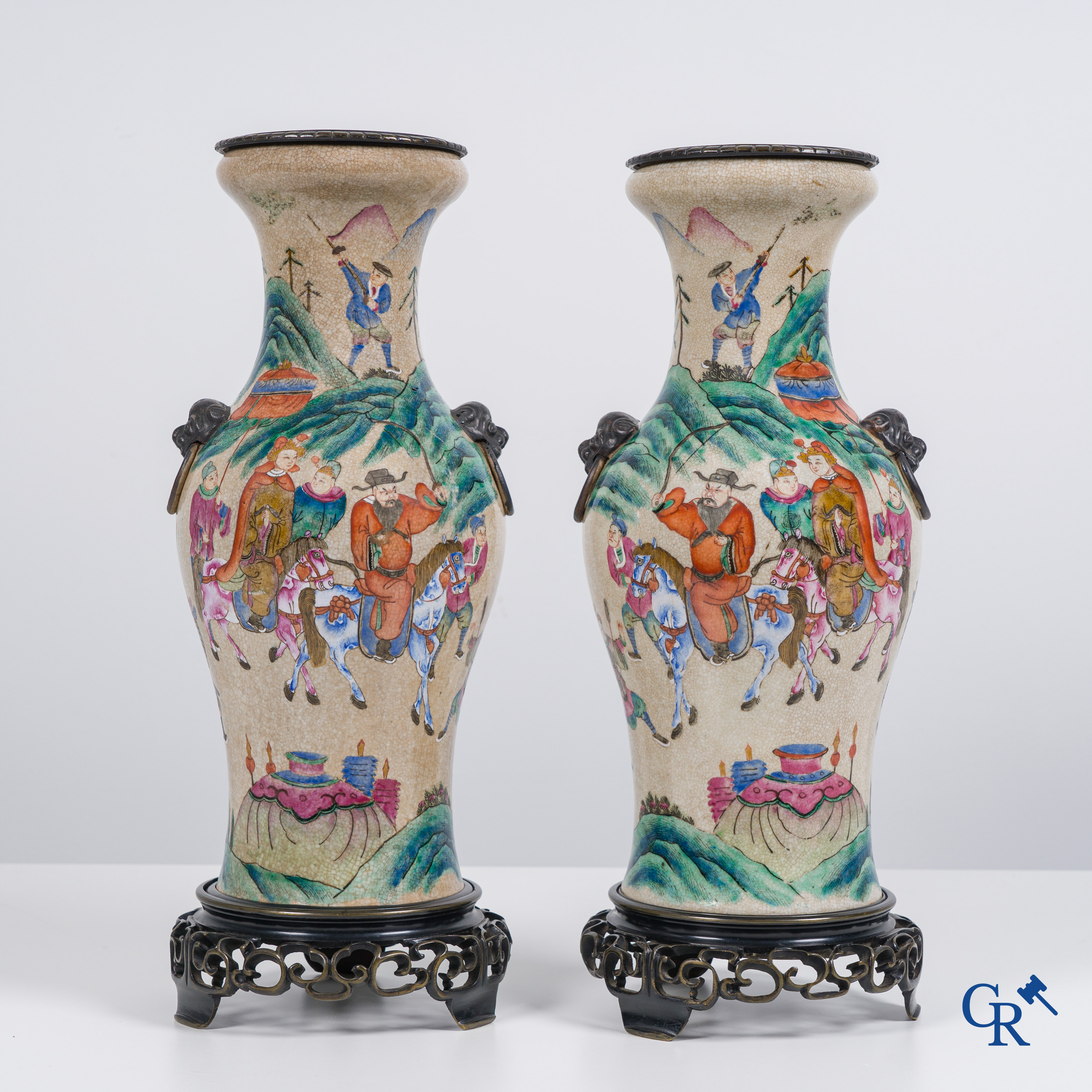 Asian Art: Chinese porcelain. A pair of finely decorated famille rose vases in a bronze frame. 19th century.