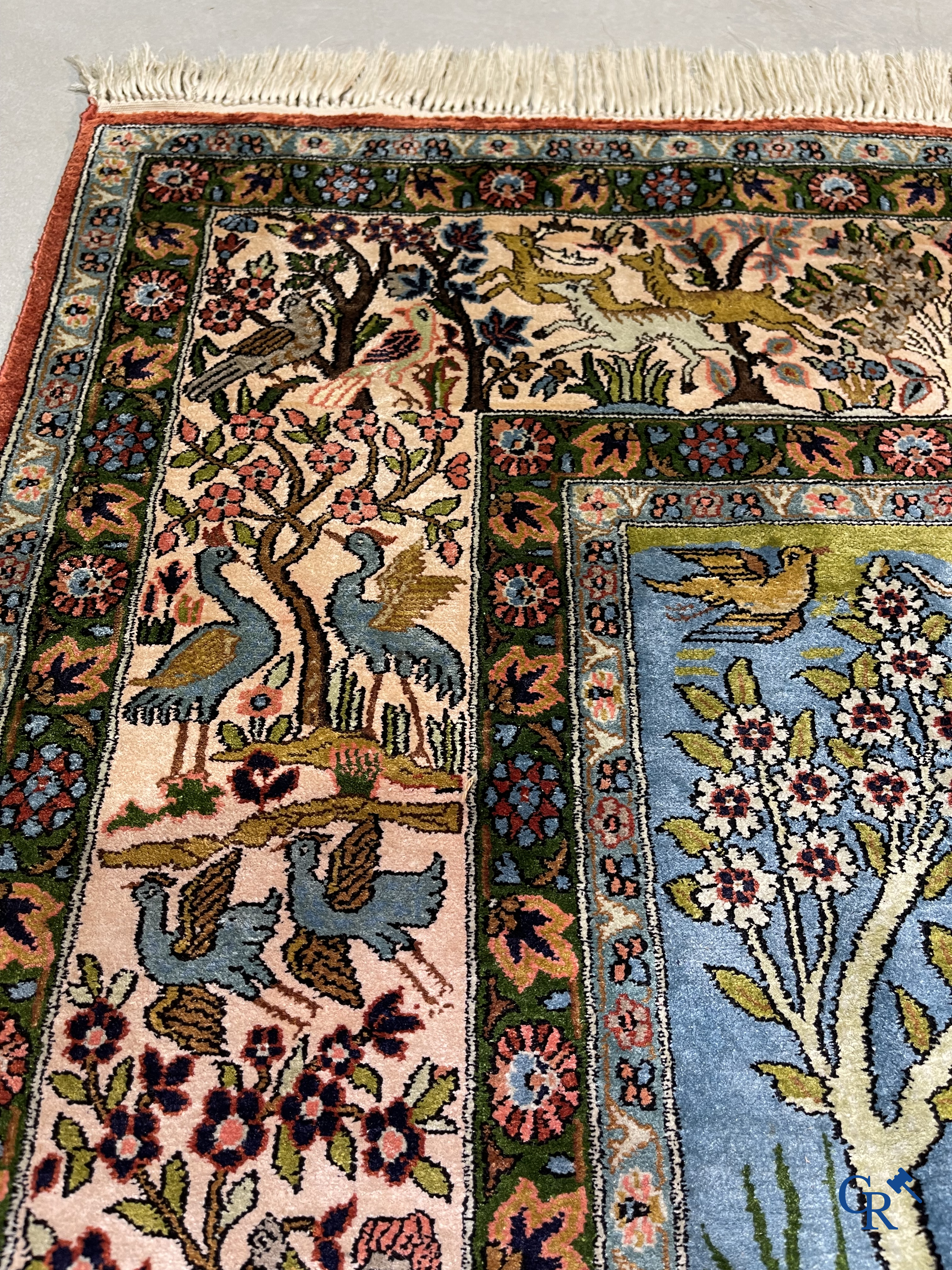 Tapis d'Orient. Iran. Un tapis persan en soie finement noué à la main avec des personnages et un cheval dans un paysage.