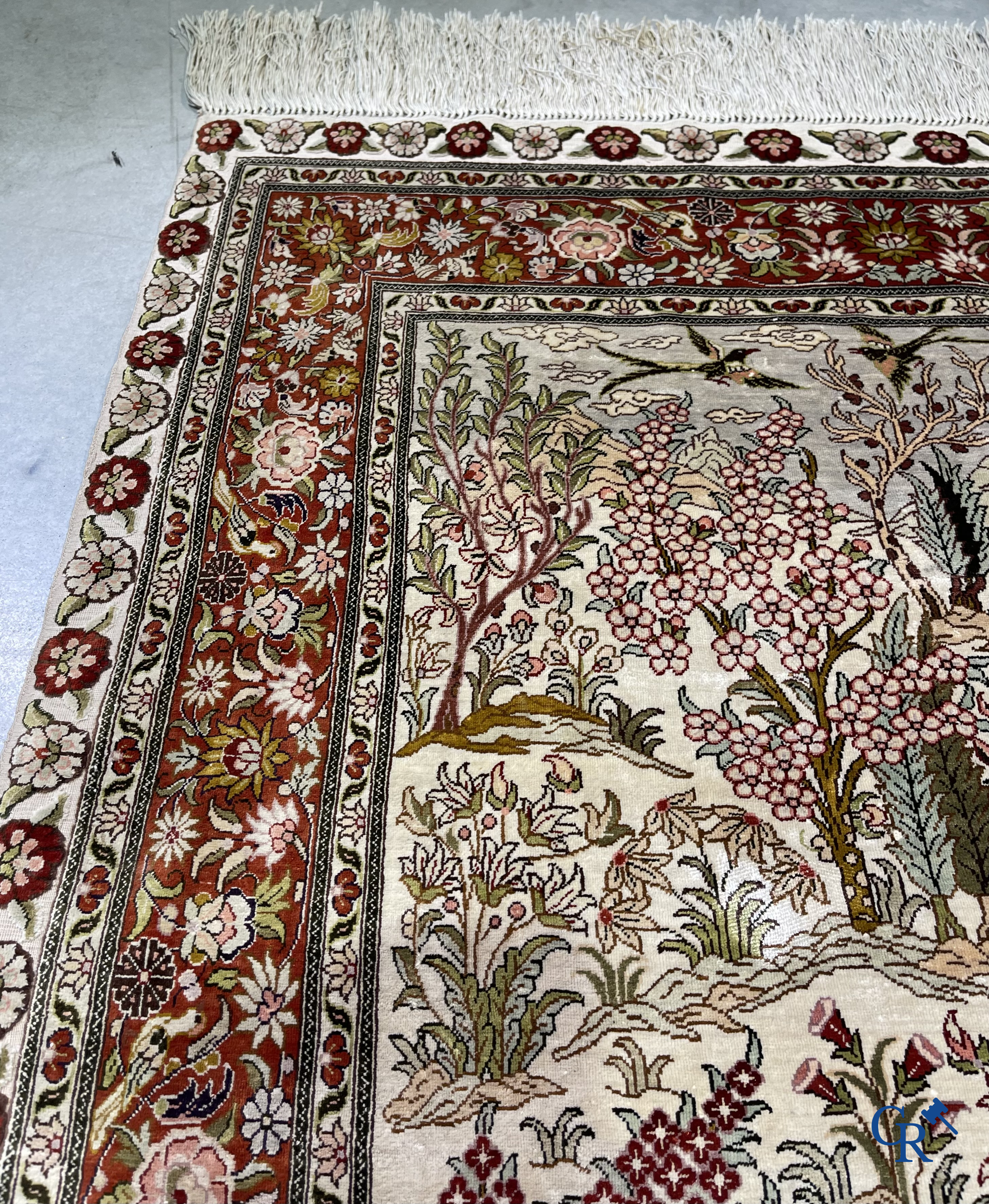 Tapis d'Orient: Un tapis en soie finement noué à la main avec des oiseaux aquatiques dans un paysage sur fond floral.