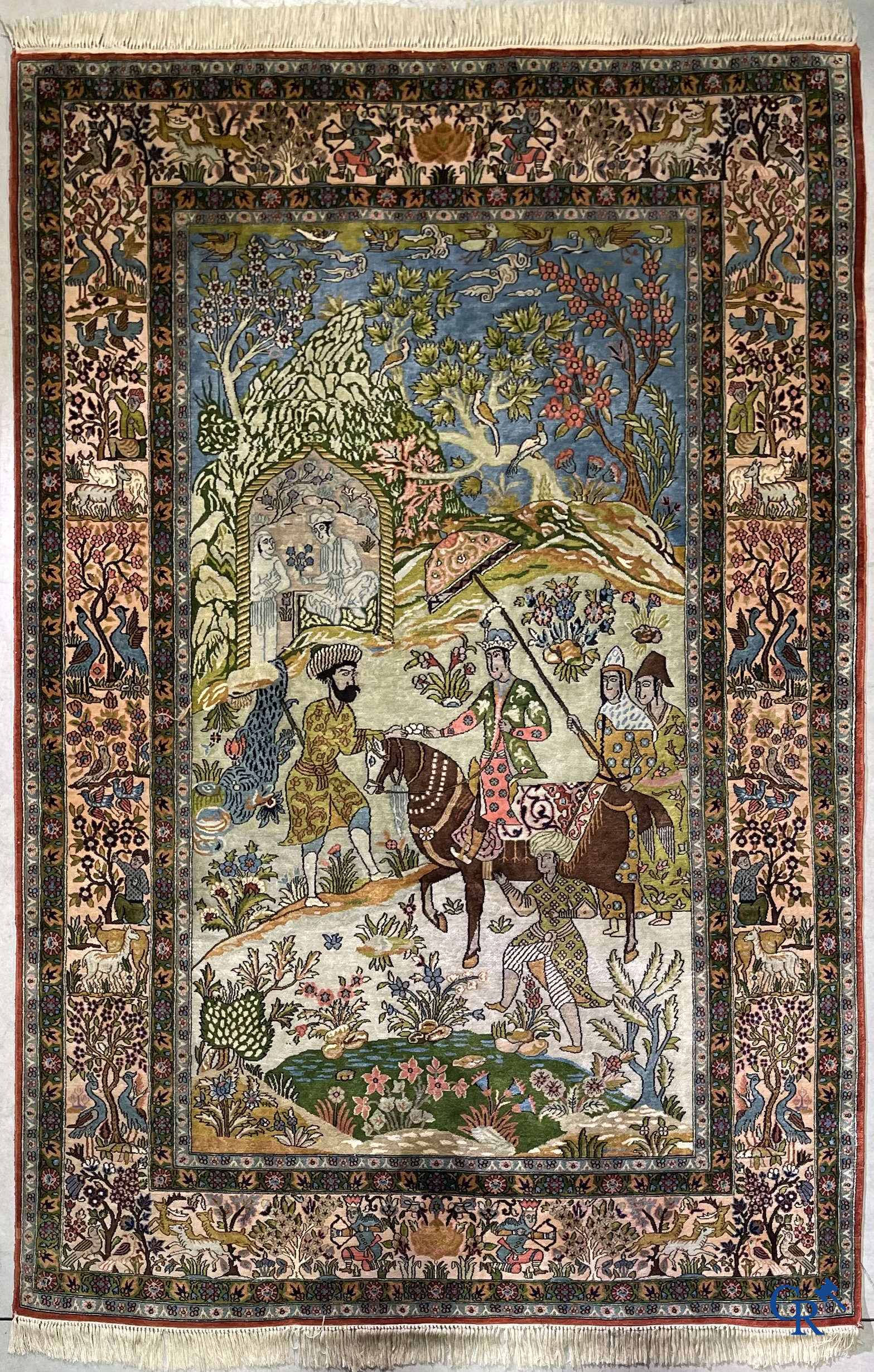 Tapis d'Orient. Iran. Un tapis persan en soie finement noué à la main avec des personnages et un cheval dans un paysage.