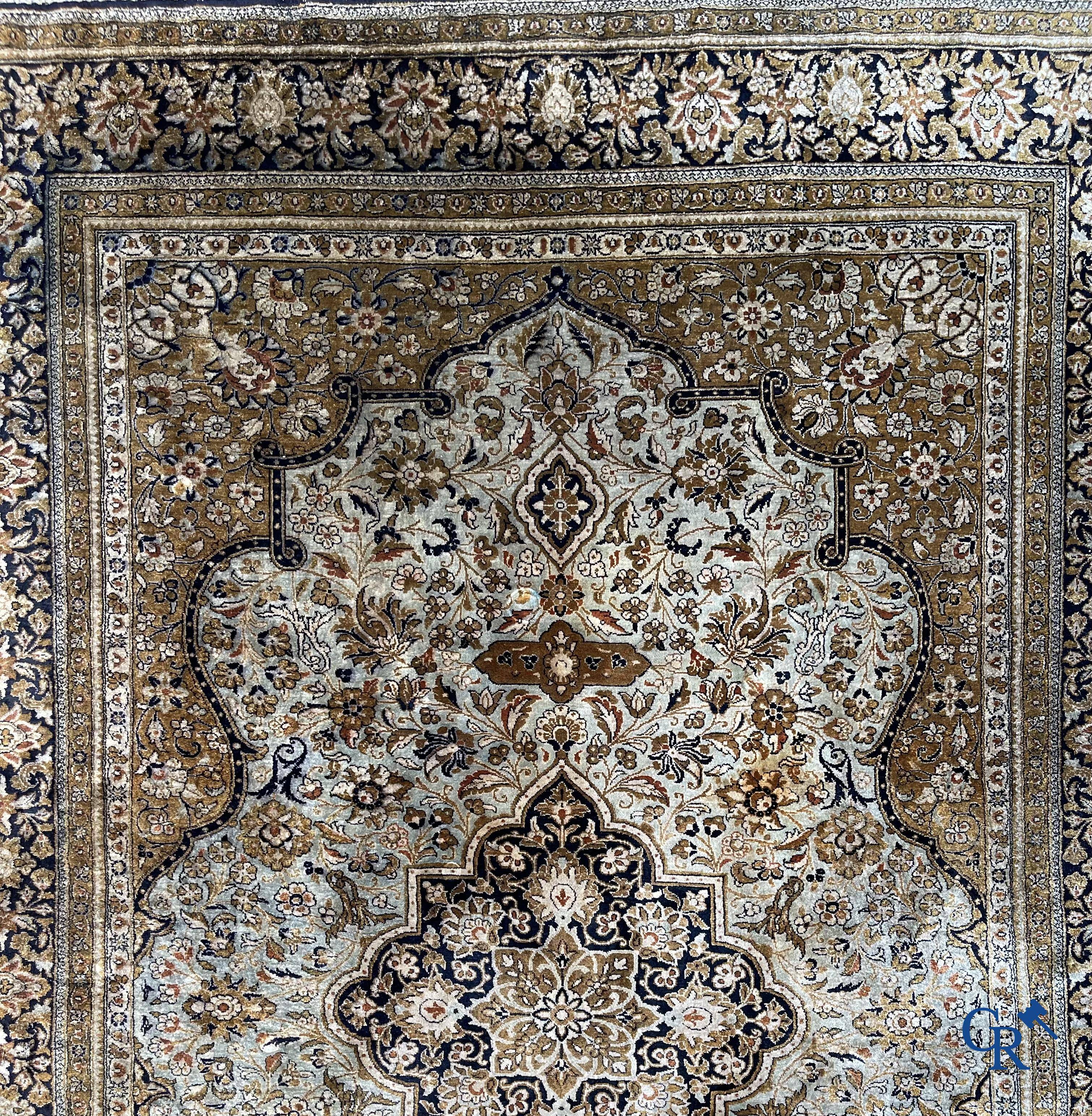 Tapis d'Orient. Un tapis en soie finement noué à la main avec un décor floral.