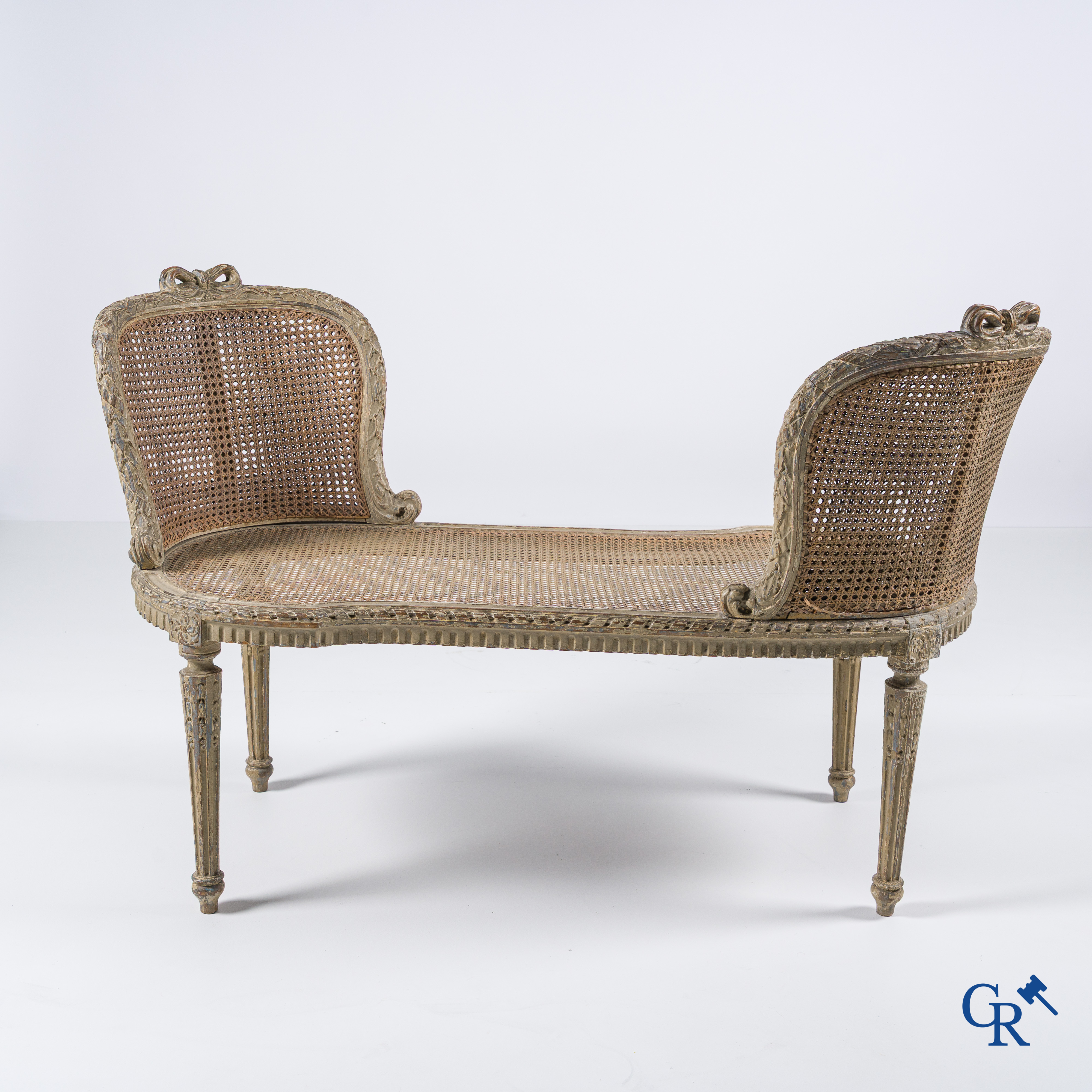 Lodewijk XVI-periode. Een grijs gepatineerd en hout gesculpteerd LXVI banket met cannage. Eind 18e eeuw.