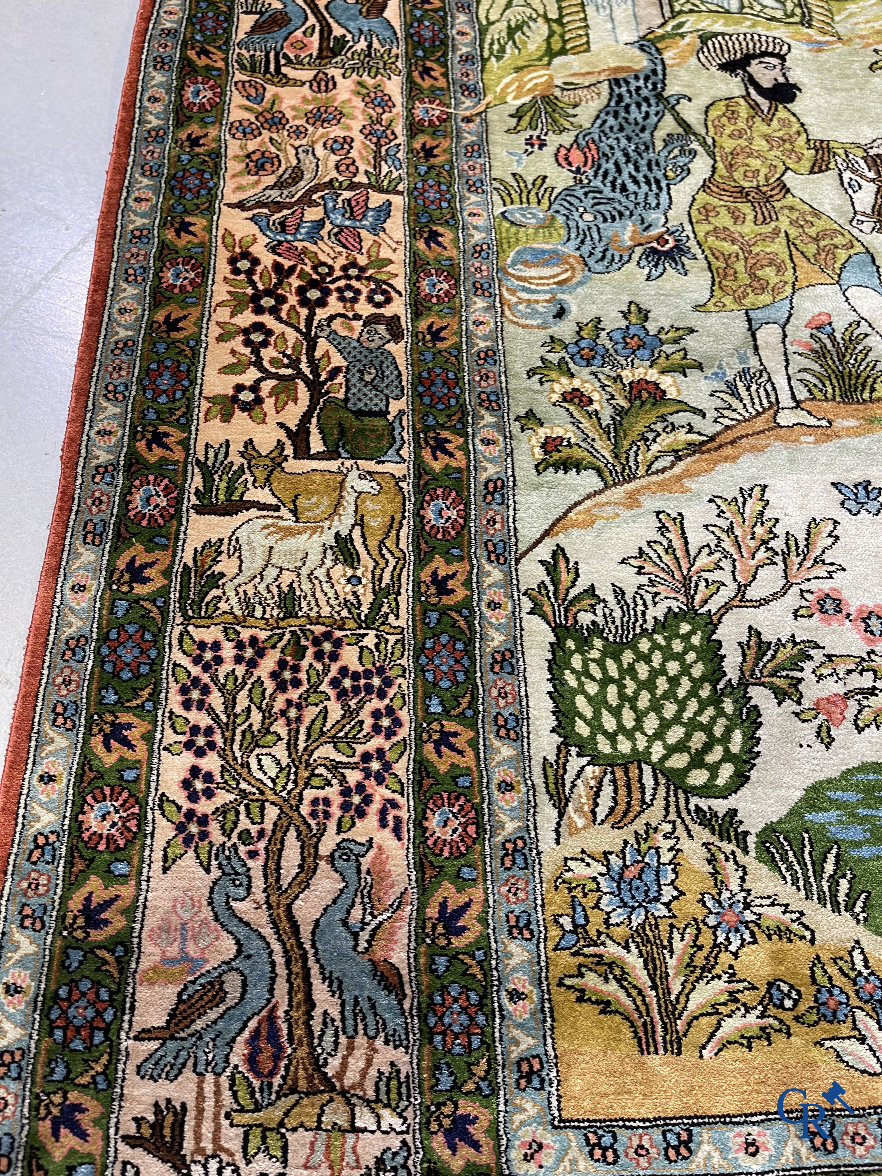 Tapis d'Orient. Iran. Un tapis persan en soie finement noué à la main avec des personnages et un cheval dans un paysage.