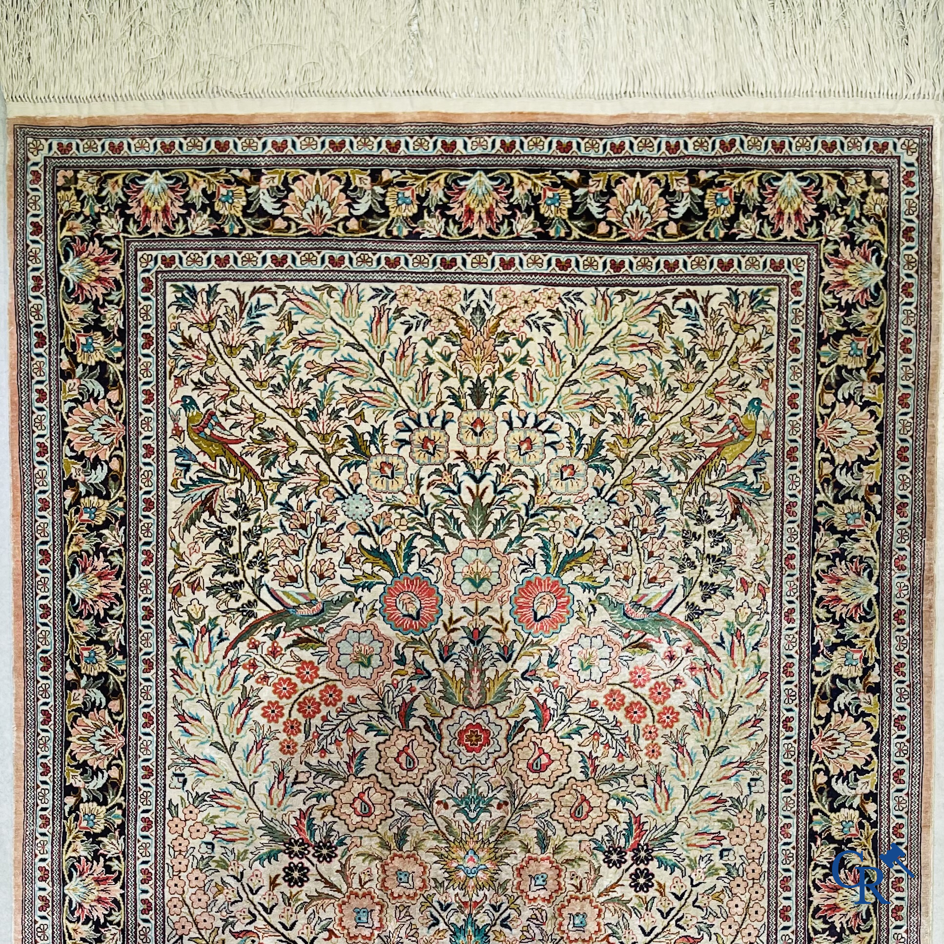 Tapis d'Orient: Un tapis persan en soie finement noué à la main avec un vase à fleurs et des oiseaux dans un décor floral.