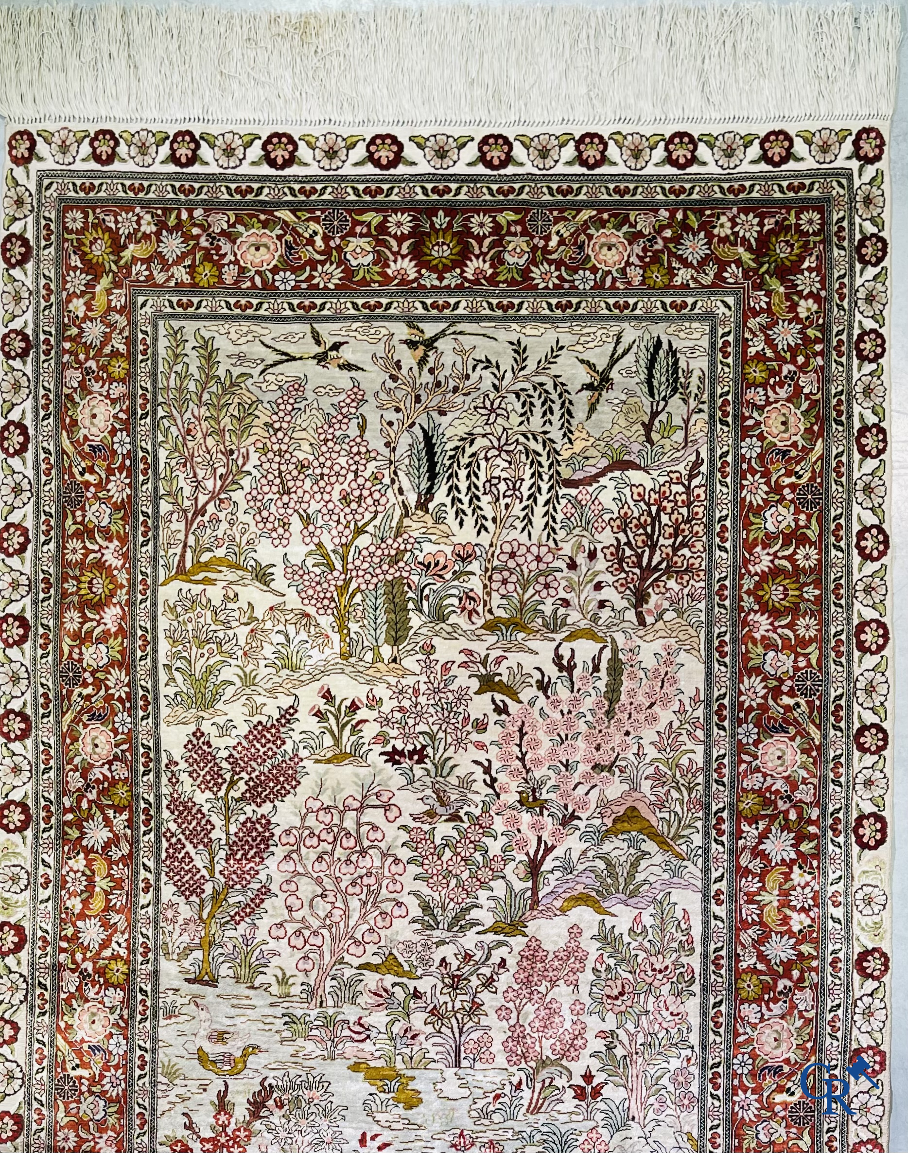 Tapis d'Orient: Un tapis en soie finement noué à la main avec des oiseaux aquatiques dans un paysage sur fond floral.