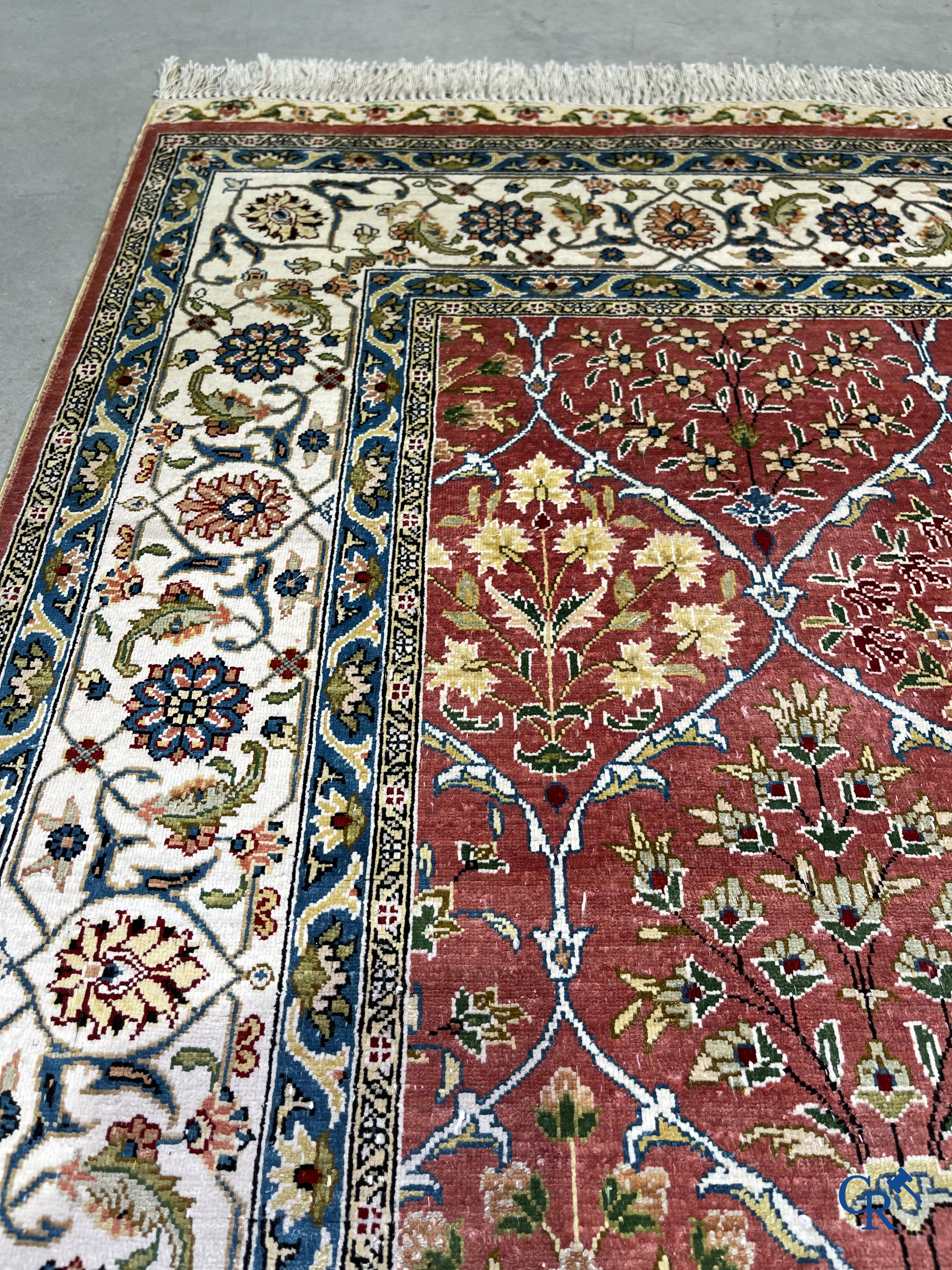 Tapis d'Orient: Un tapis finement noué à la main en laine et soie avec un décor floral.<br />
Signé.