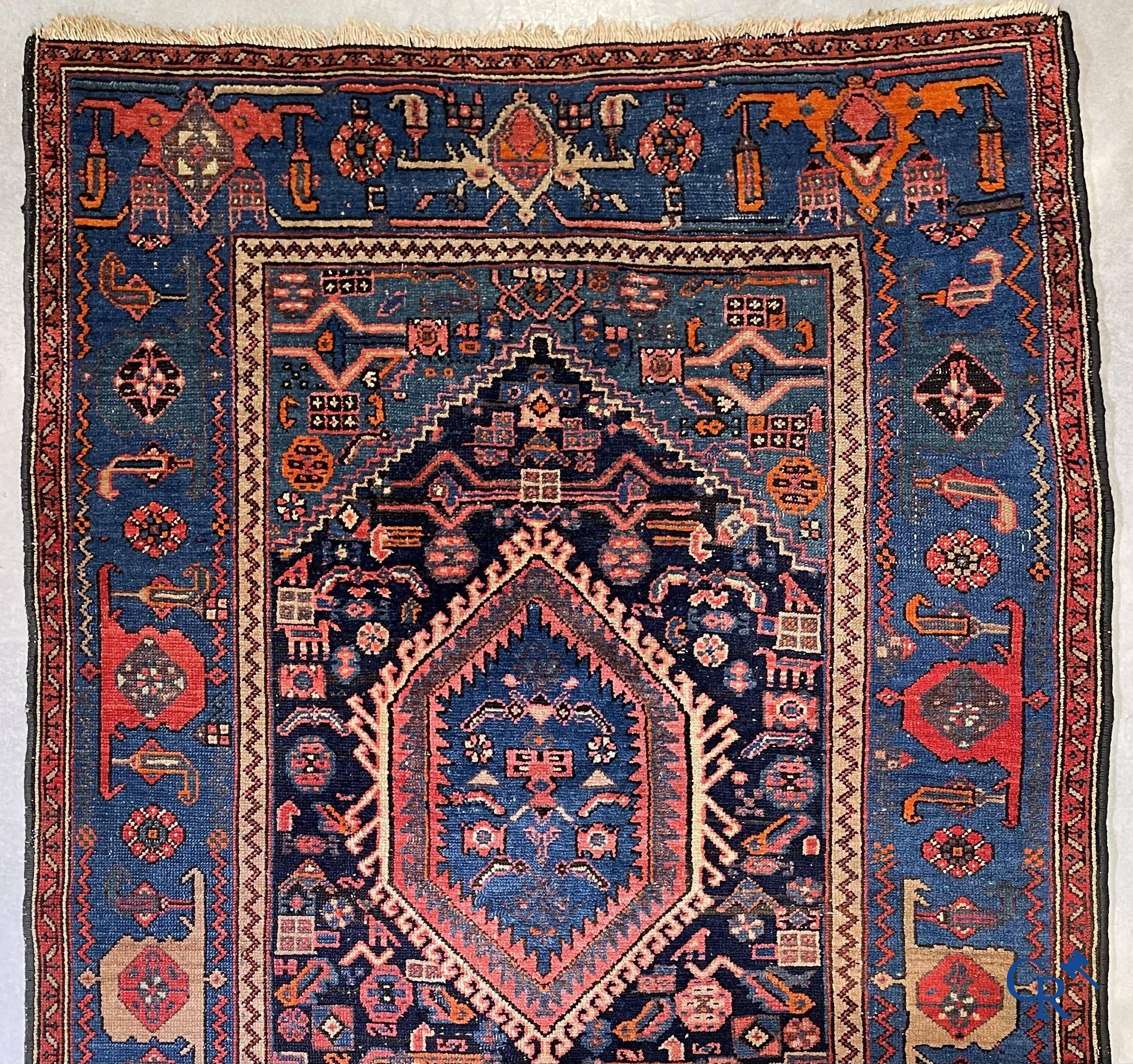 Antique Oriental carpets, an antique hand-knotted carpet with motifs on a blue background.