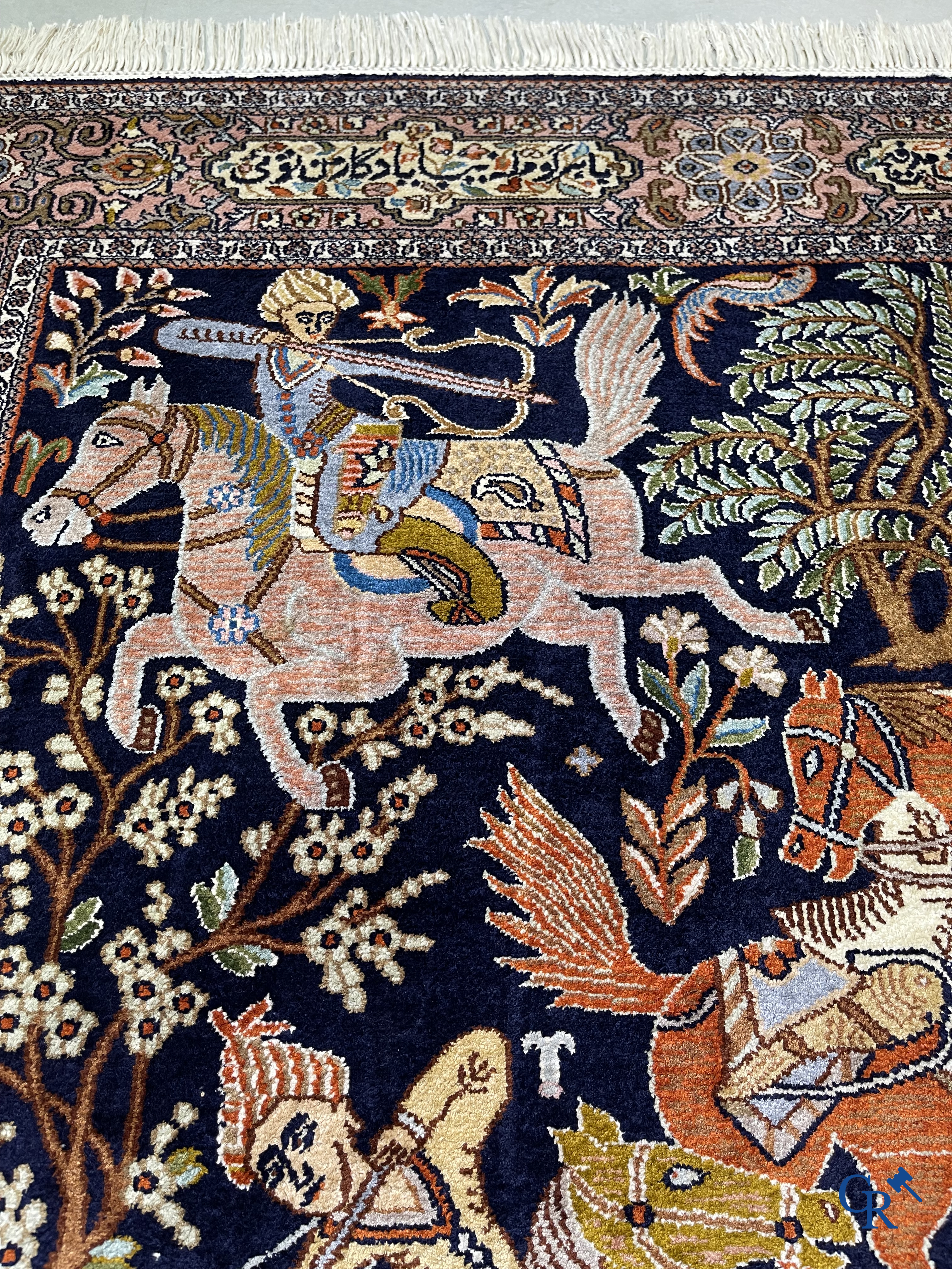 Oriental rugs. Iran. A finely hand-knotted Persian rug in wool and silk with hunters on horseback and inscriptions.