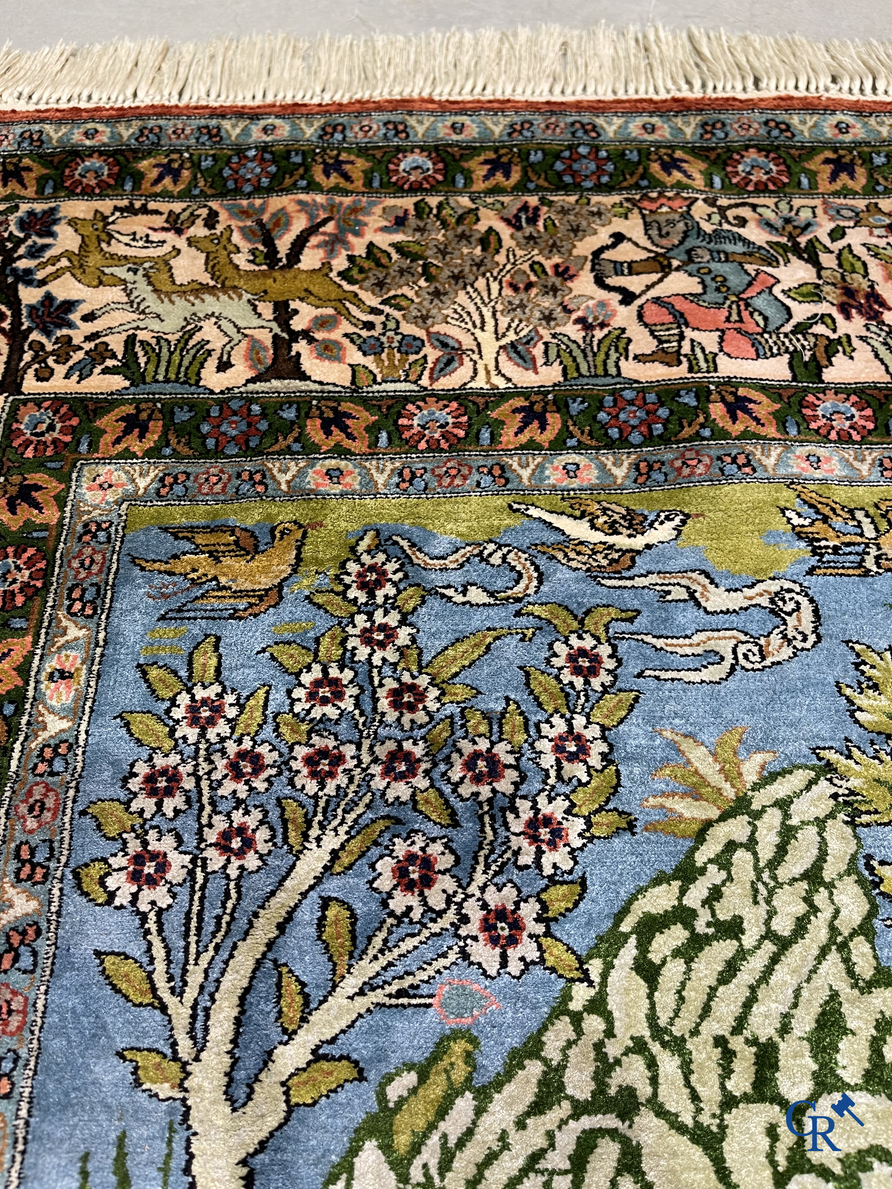 Tapis d'Orient. Iran. Un tapis persan en soie finement noué à la main avec des personnages et un cheval dans un paysage.