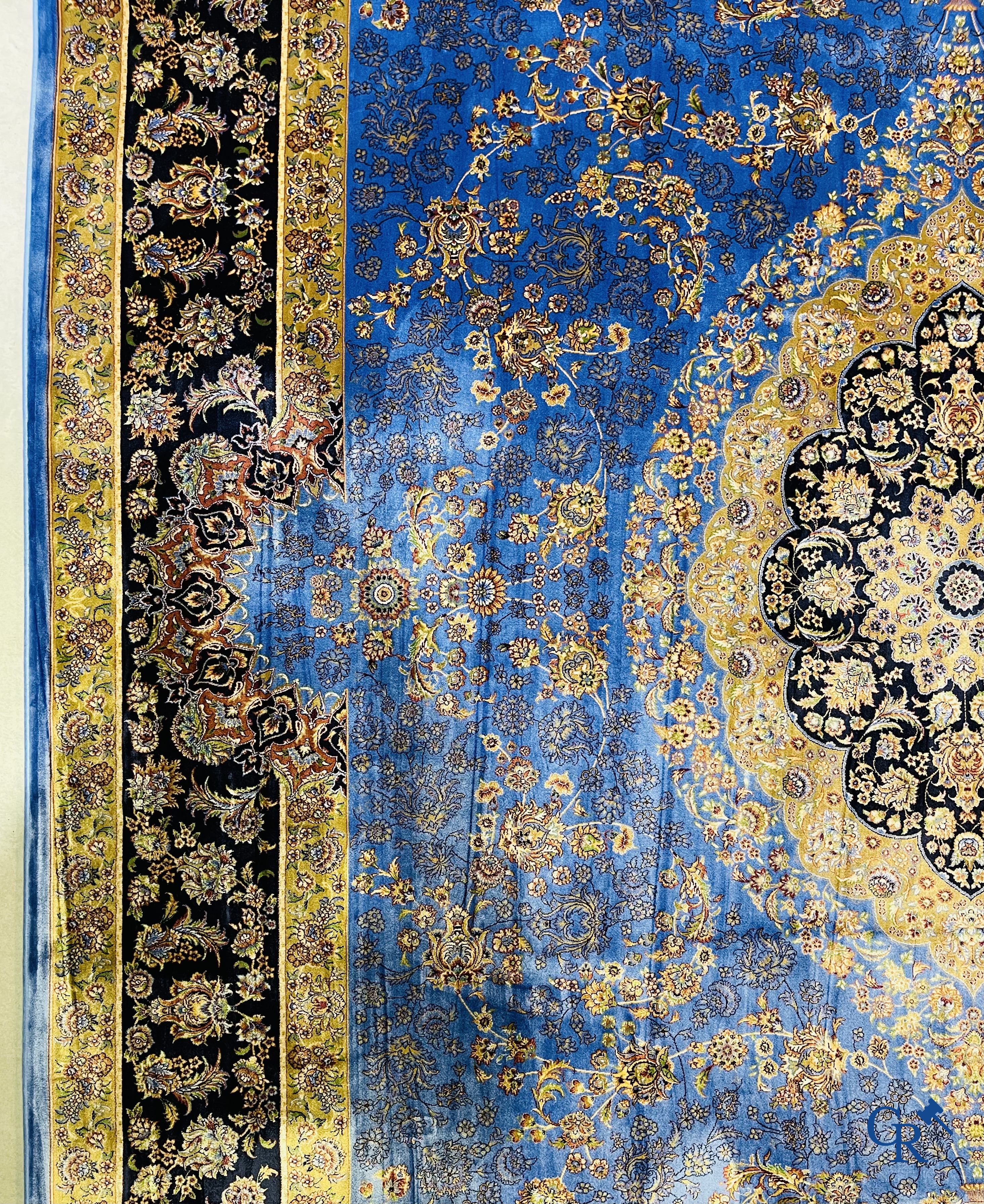 Tapis. Exceptionnel tapis en soie avec un décor floral sur fond bleu.