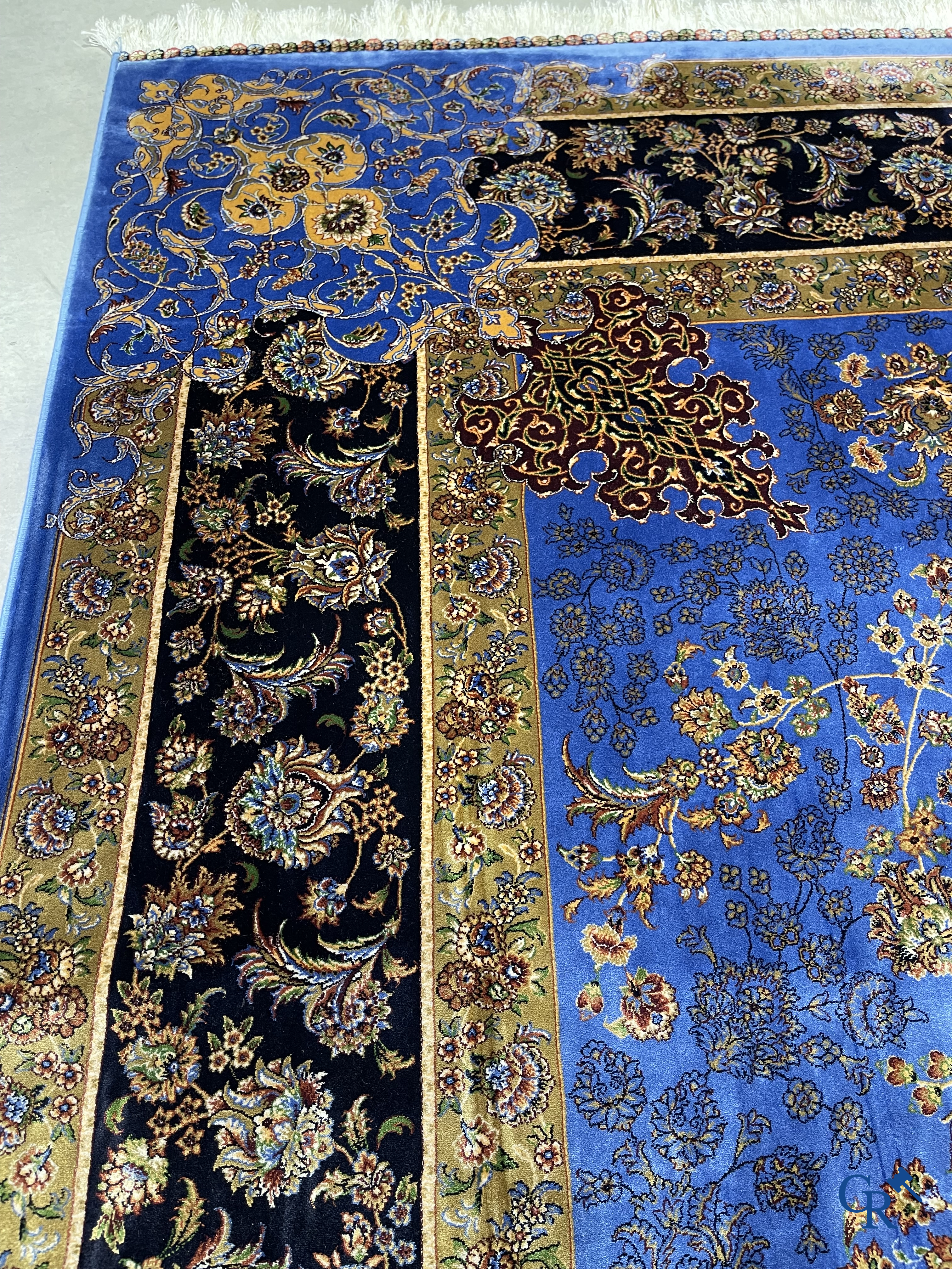 Tapis. Exceptionnel tapis en soie avec un décor floral sur fond bleu.