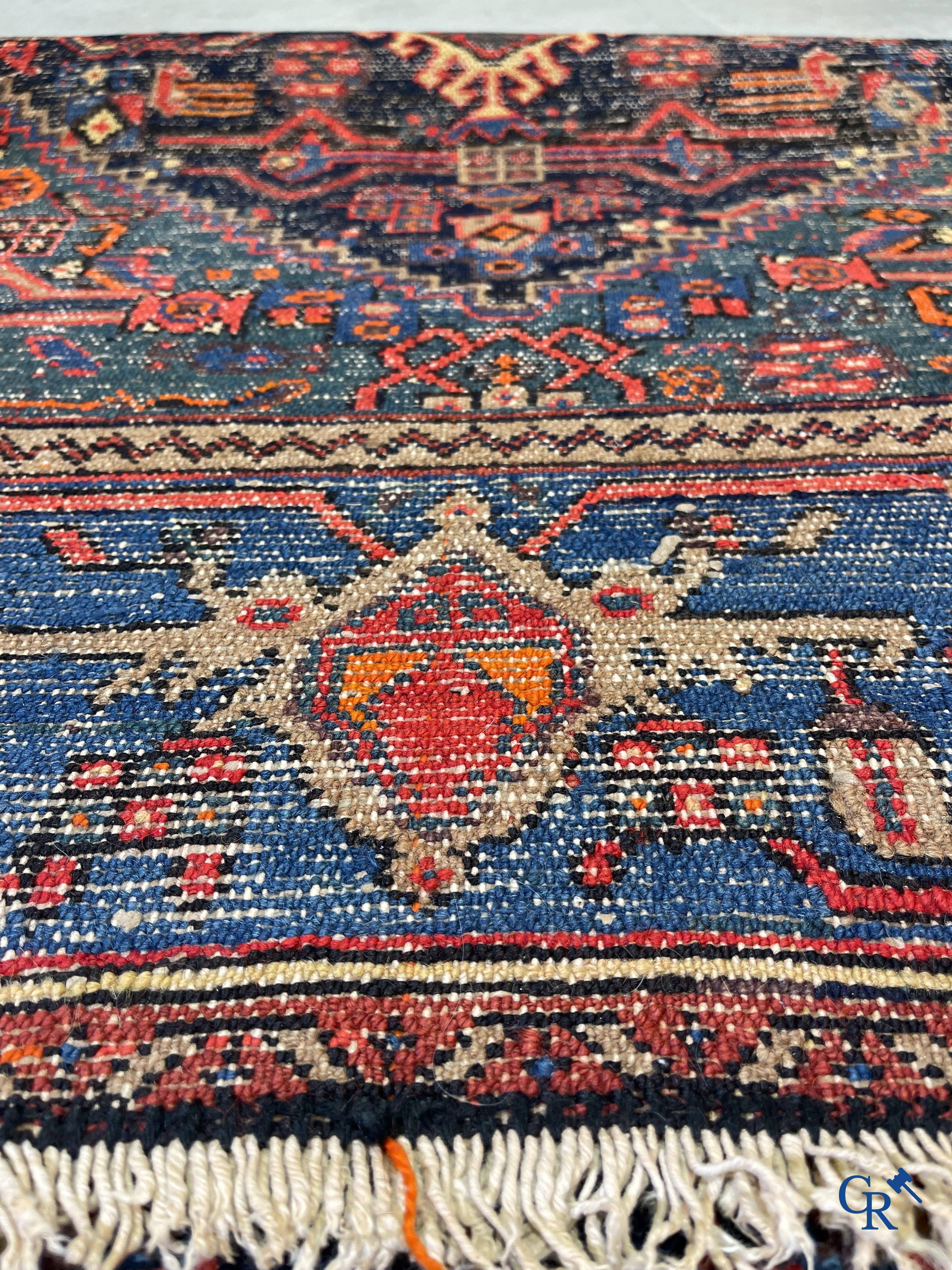 Antique Oriental carpets, an antique hand-knotted carpet with motifs on a blue background.