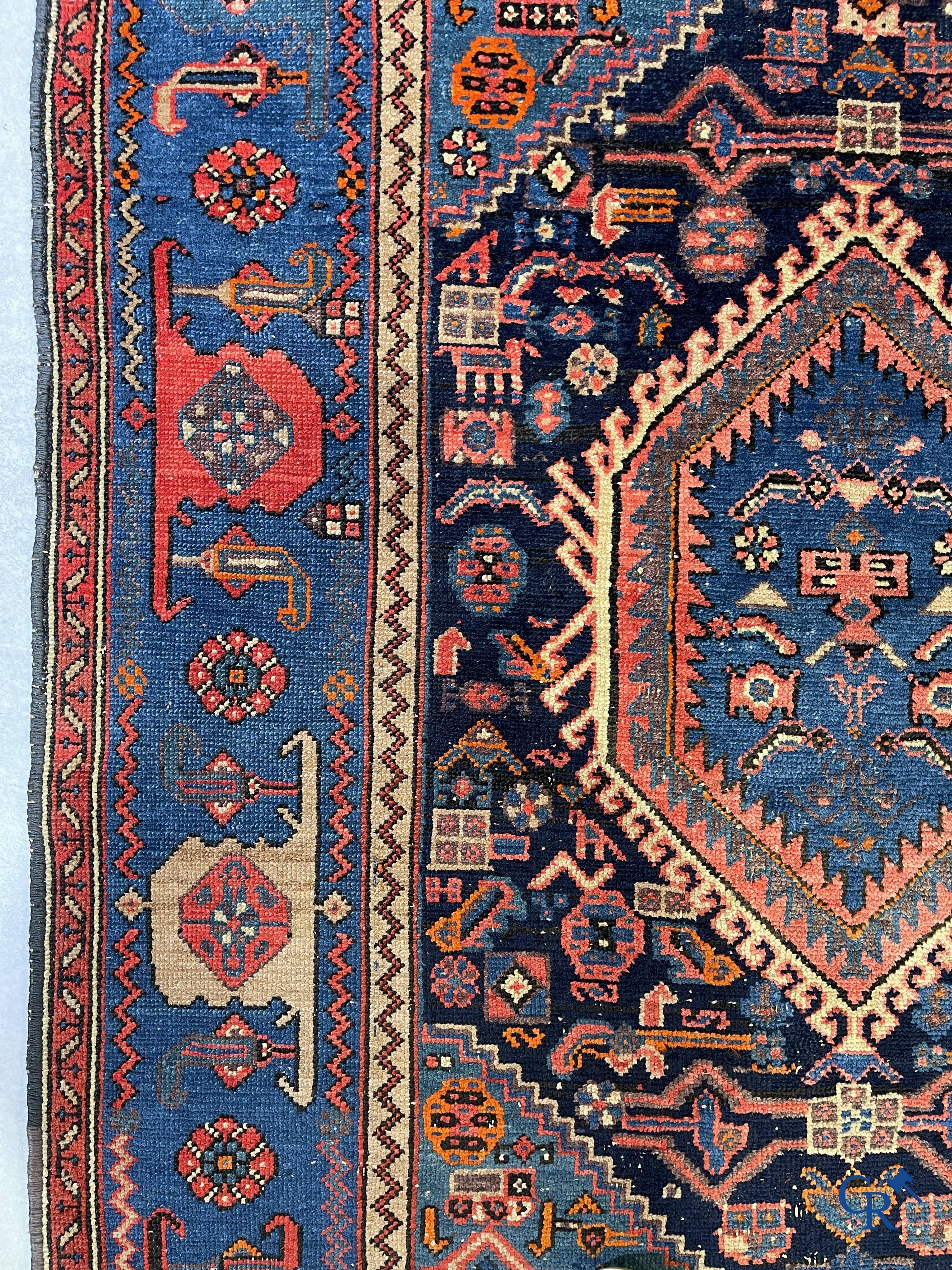 Antique Oriental carpets, an antique hand-knotted carpet with motifs on a blue background.