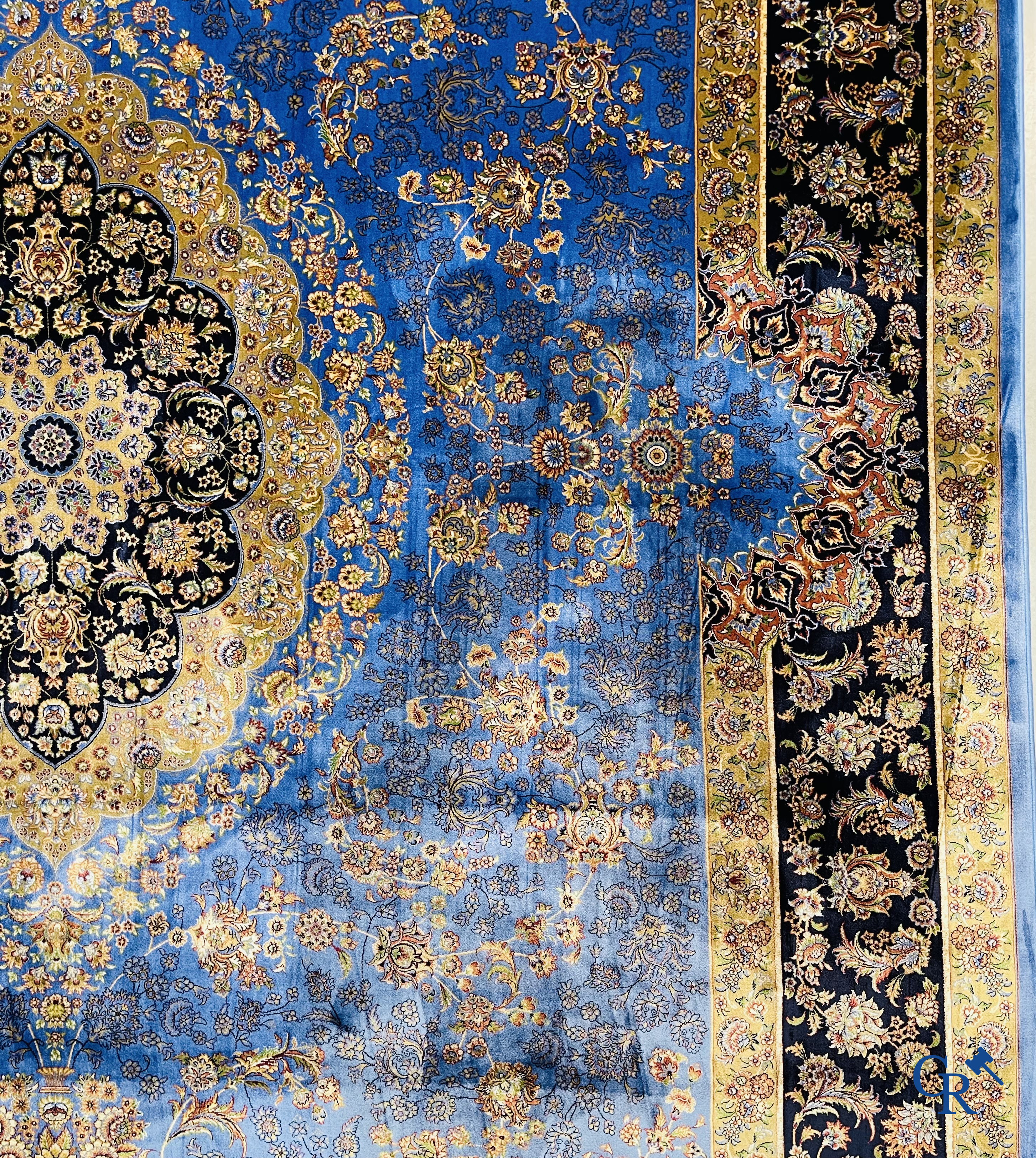 Tapis. Exceptionnel tapis en soie avec un décor floral sur fond bleu.