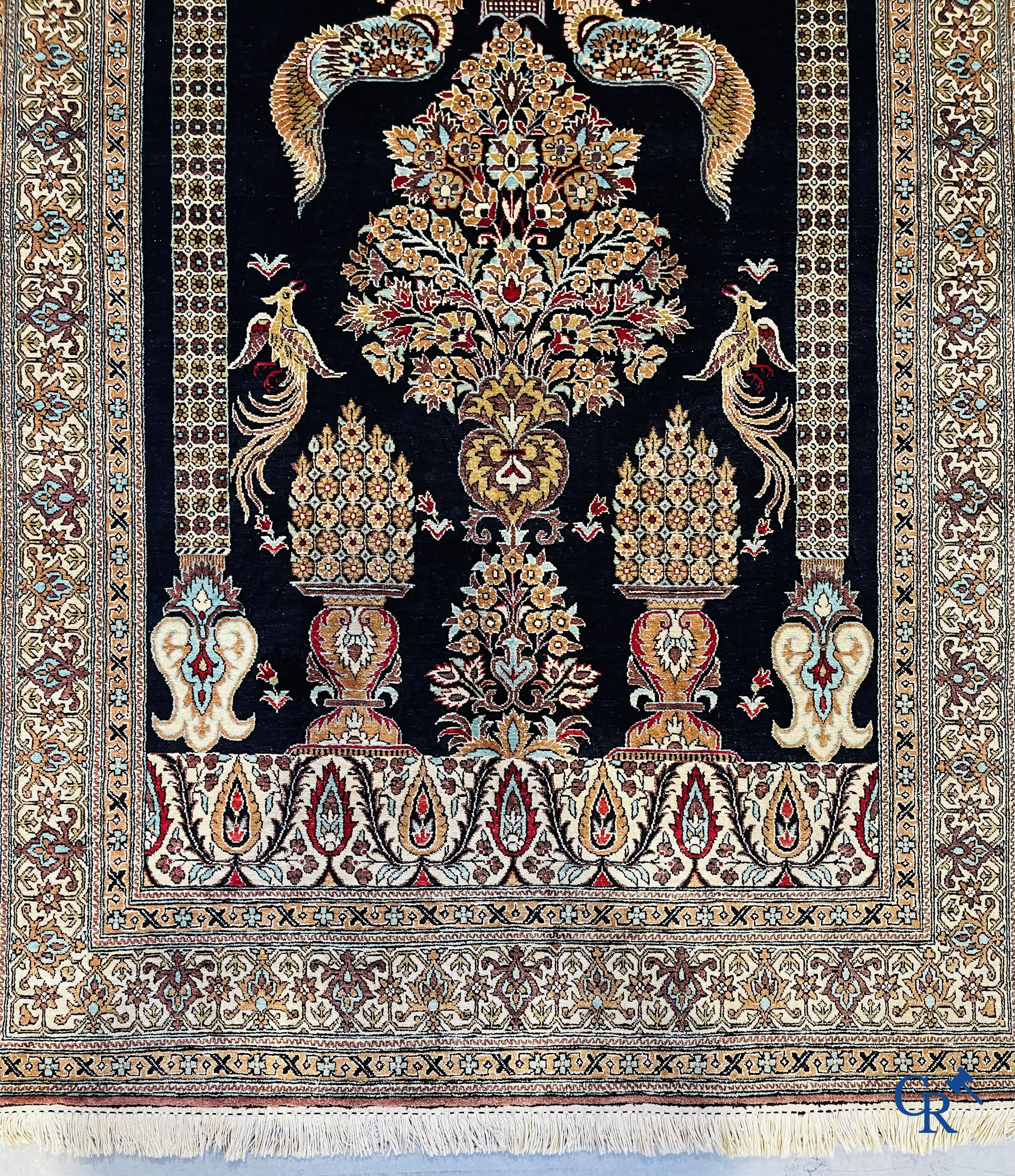 Persian carpets: A finely knotted silk Ghoum carpet with a decor of birds and flowers.