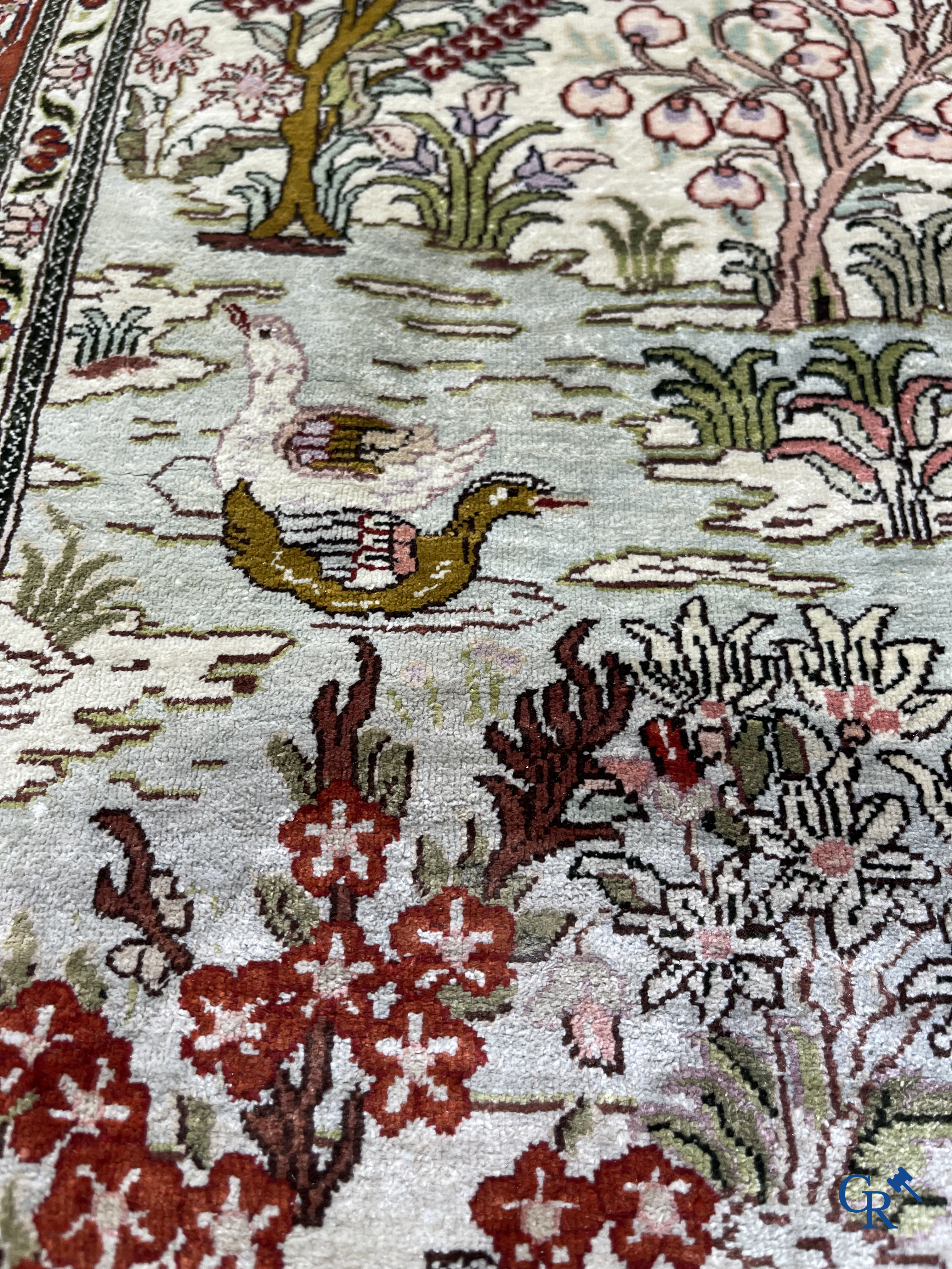 Oriental carpets: A finely hand-knotted silk carpet with water birds in a landscape on a floral background.