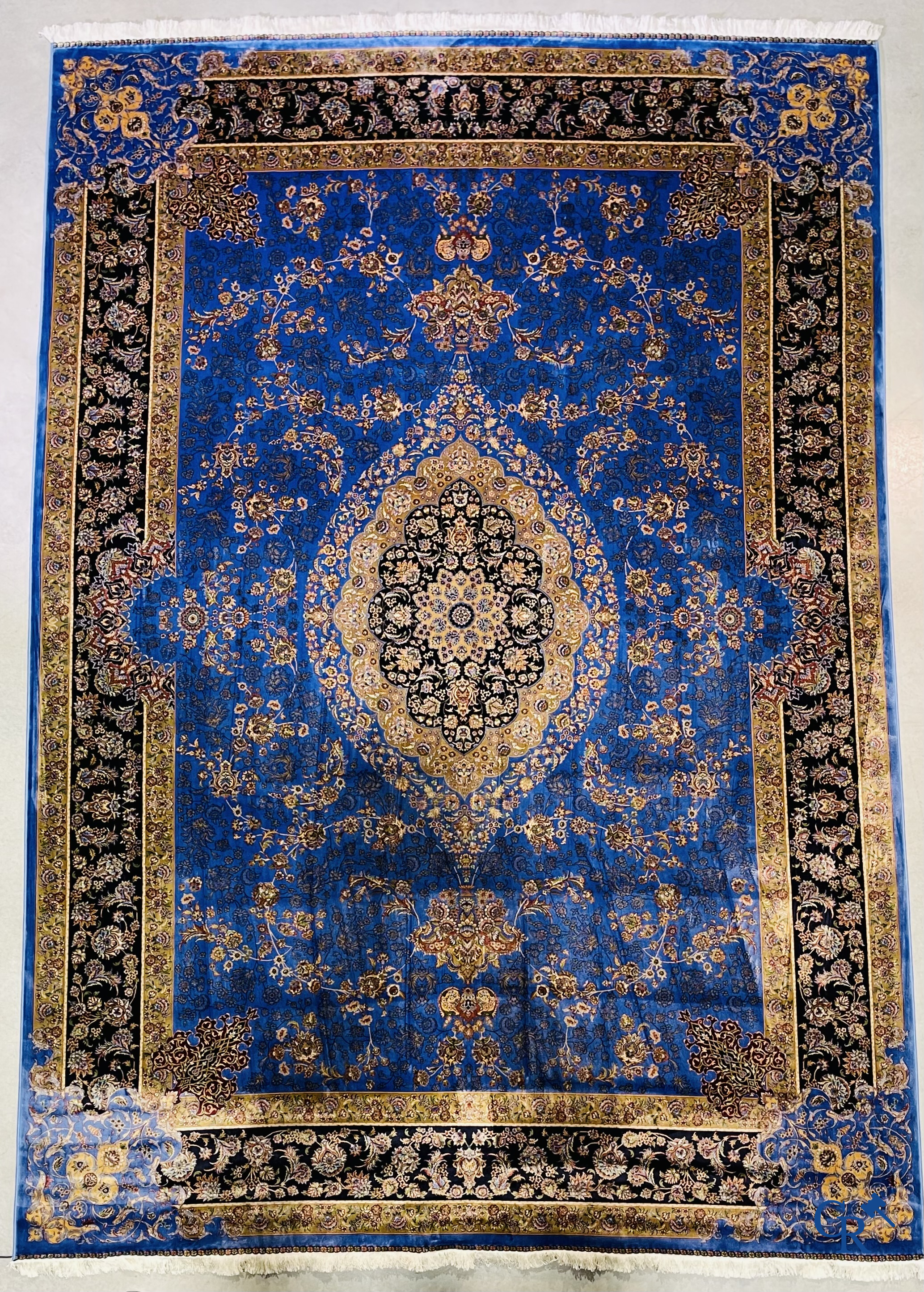 Tapis. Exceptionnel tapis en soie avec un décor floral sur fond bleu.