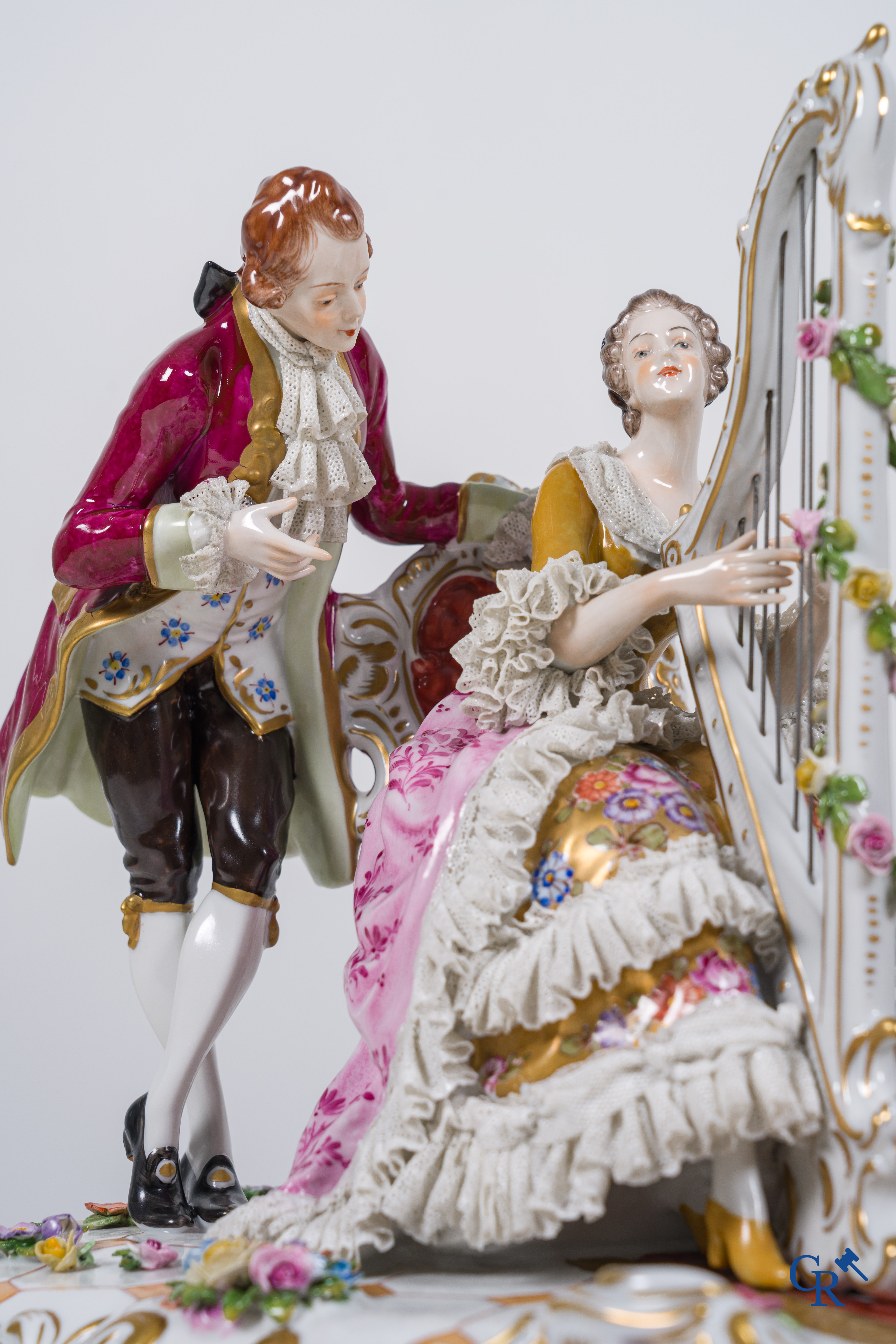 Volkstedt Rudolstadt, Grand groupe en porcelaine en dentelle, joueuse d'harpe dans un intérieur richement décoré. Marqué.