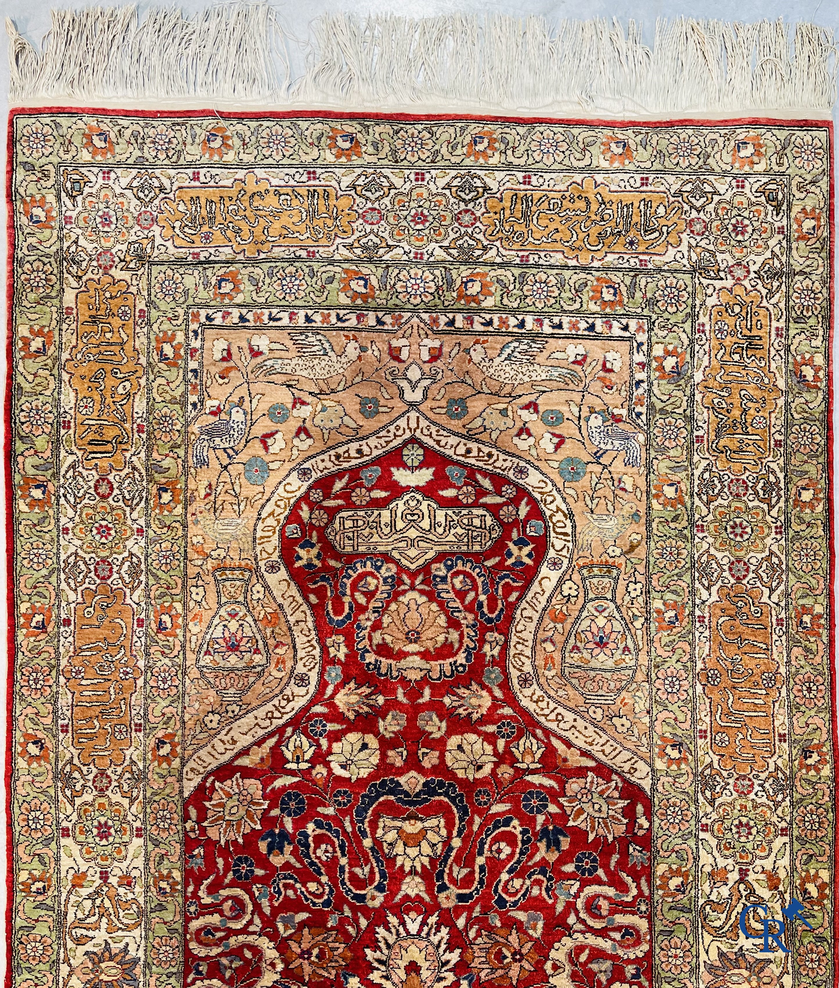 Oriental carpets: Hereke, a finely knotted silk carpet with inscriptions and birds in a floral decor.