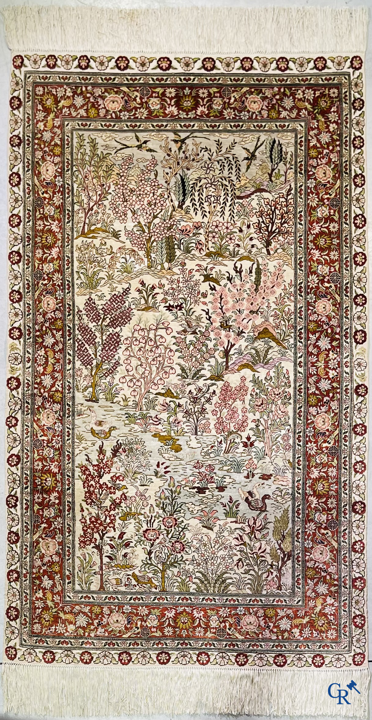 Tapis d'Orient: Un tapis en soie finement noué à la main avec des oiseaux aquatiques dans un paysage sur fond floral.