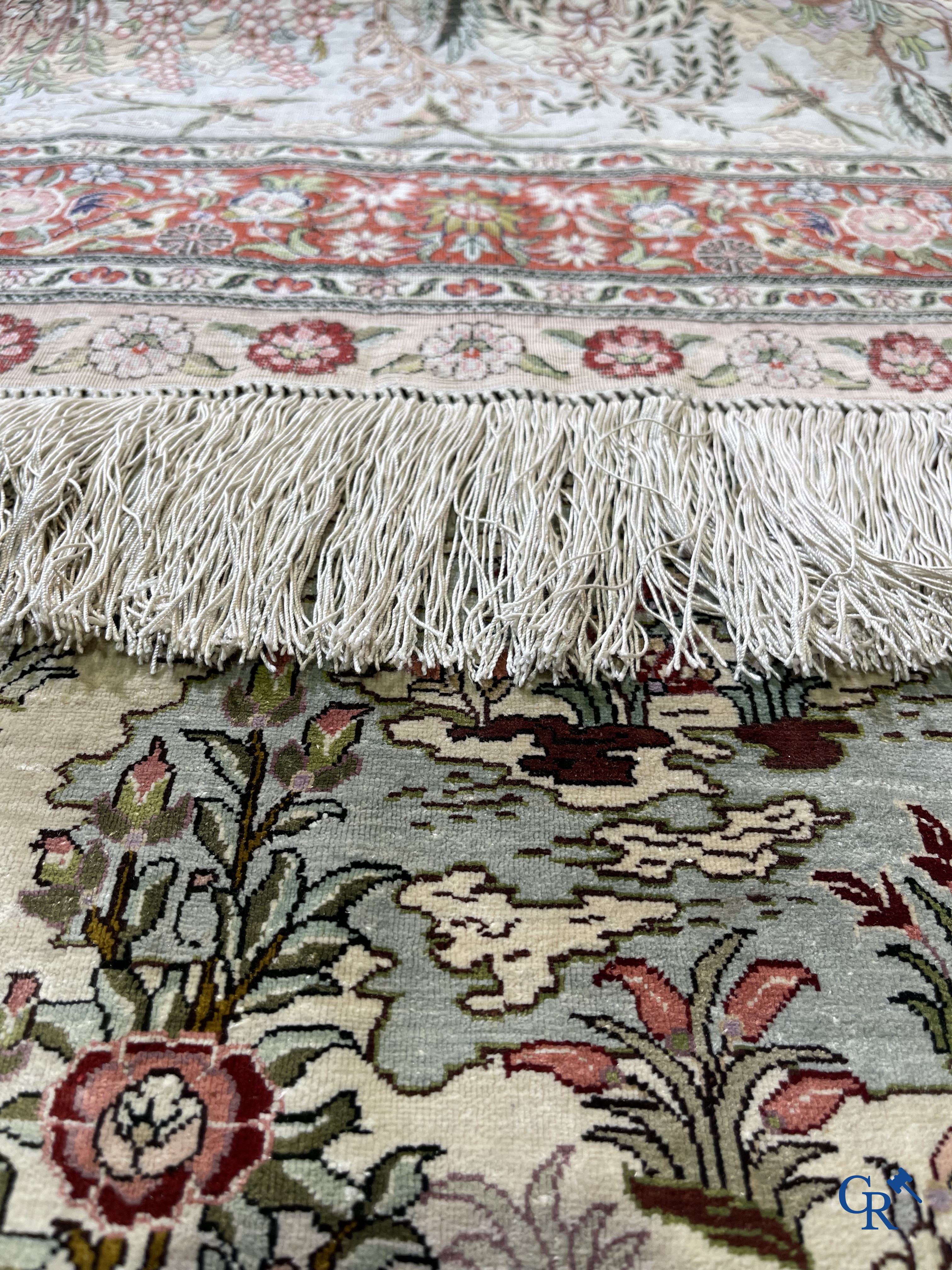 Tapis d'Orient: Un tapis en soie finement noué à la main avec des oiseaux aquatiques dans un paysage sur fond floral.