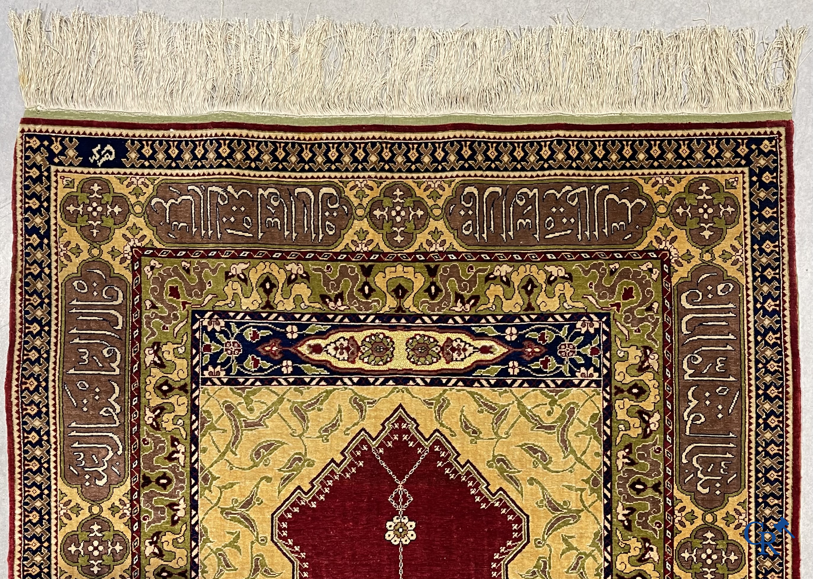 Oosterse tapijten. Een uiterst fijn handgeknoopt zijden tapijt met inscripties en gouddraad. Gesigneerd.