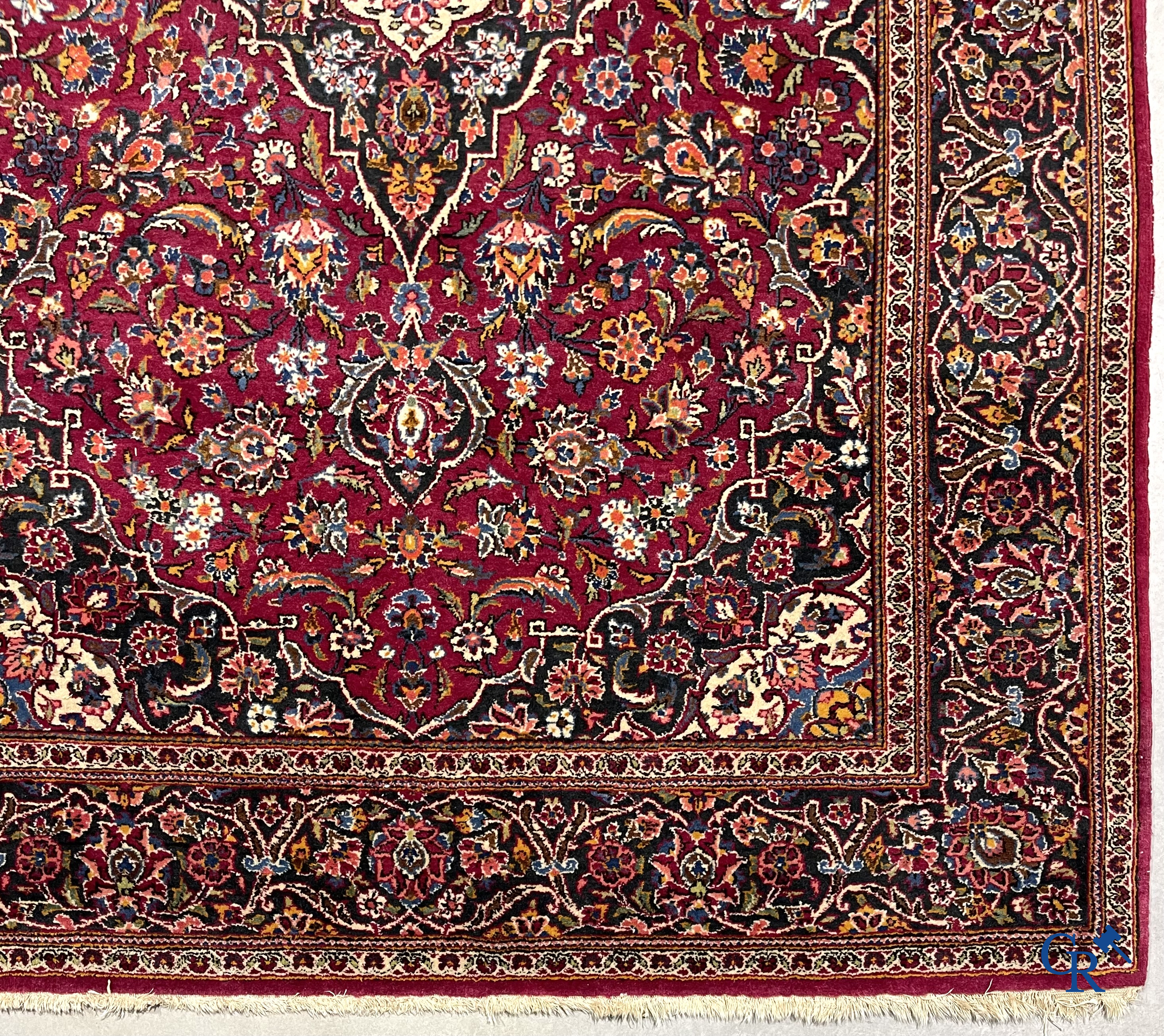 Oosterse tapijten. Een handgeknoopt oosters tapijt met floraal decor op rode achtergrond.