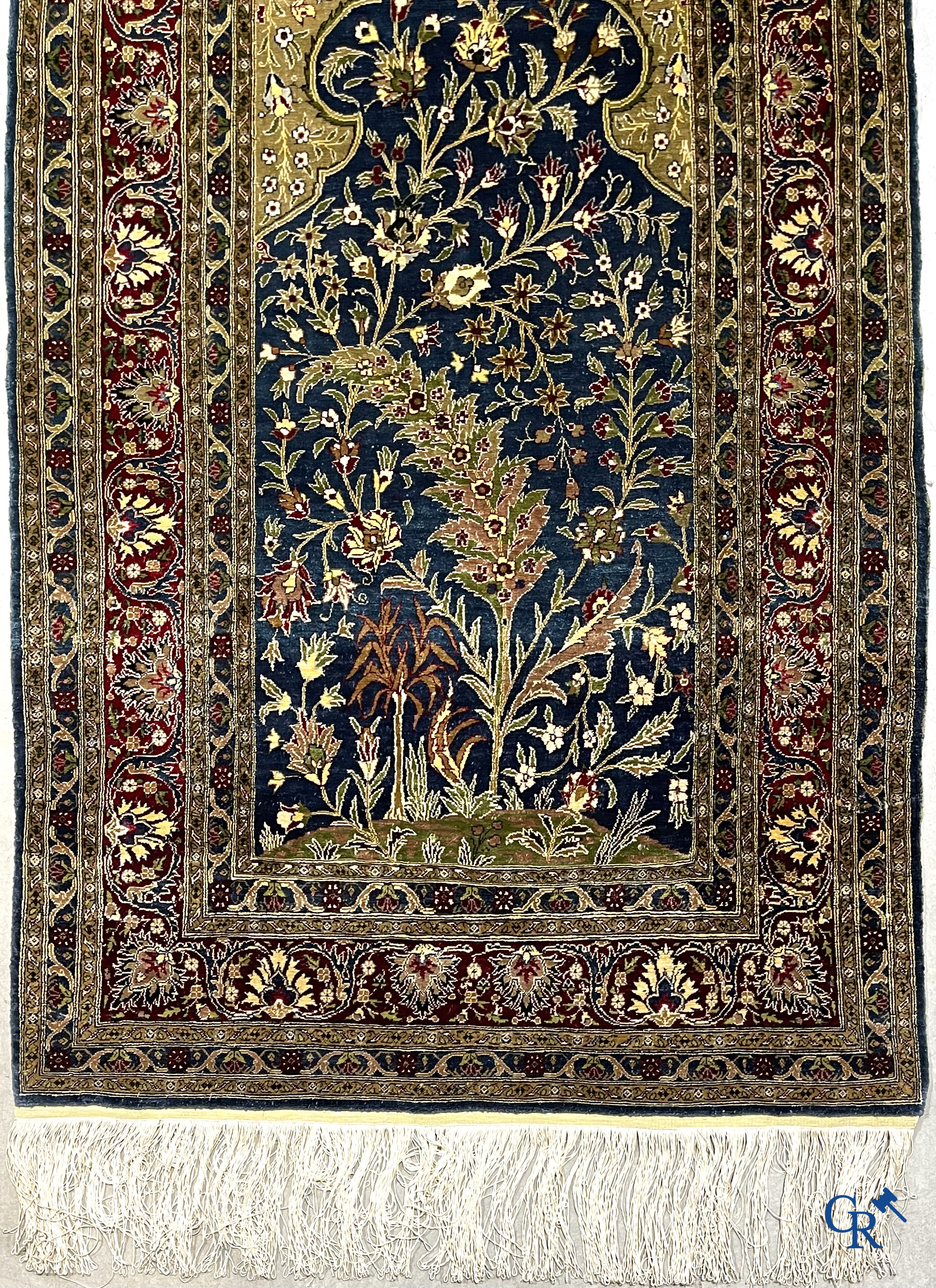 Oosterse tapijten. Een uiterst fijn geknoopt zijden tapijt met floraal decor op donker blauwe achtergrond en gouddraad.