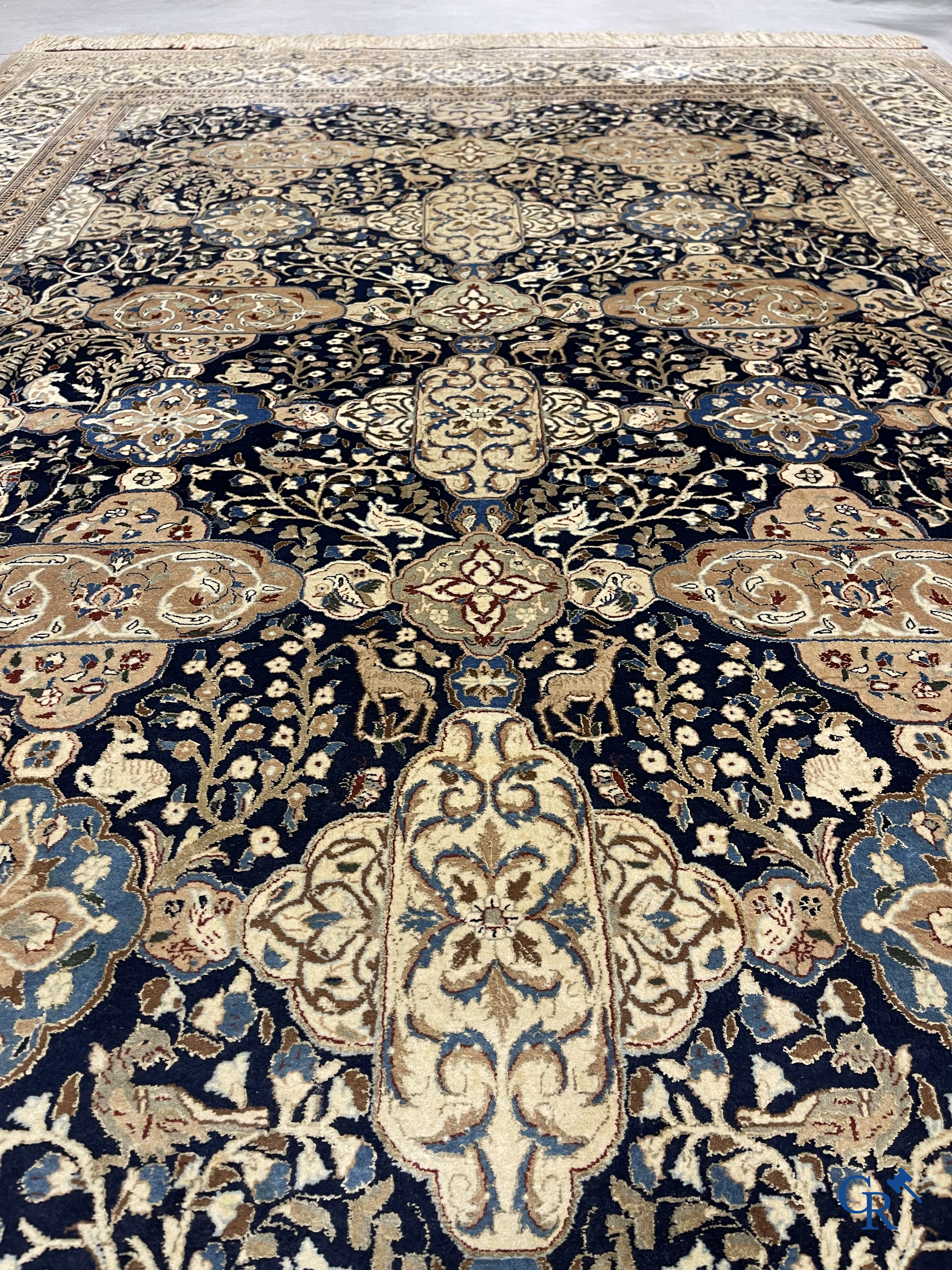 Oosterse tapijten. Een handgeknoopt tapijt met wouddieren en bloemen.