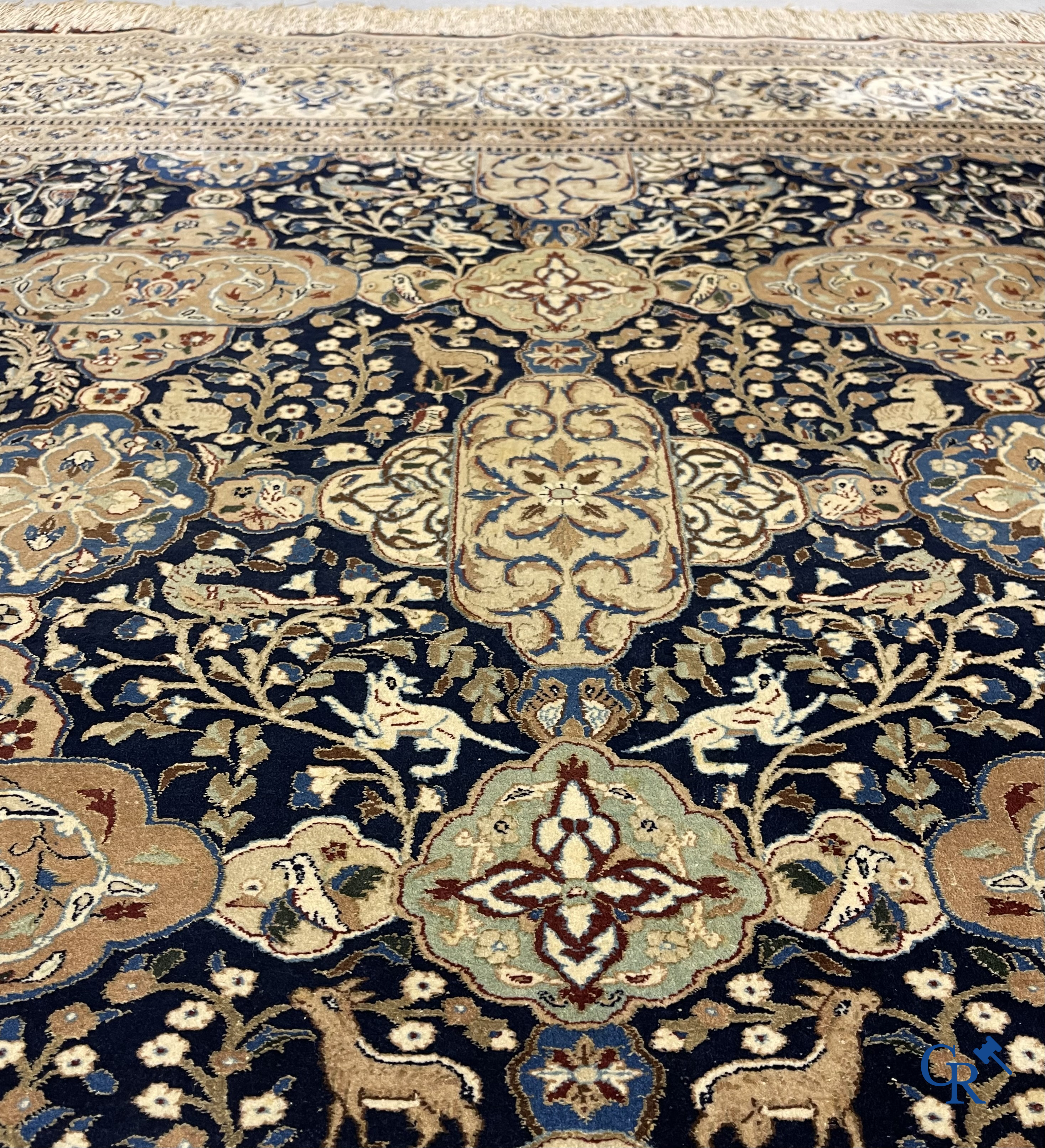 Oosterse tapijten. Een handgeknoopt tapijt met wouddieren en bloemen.