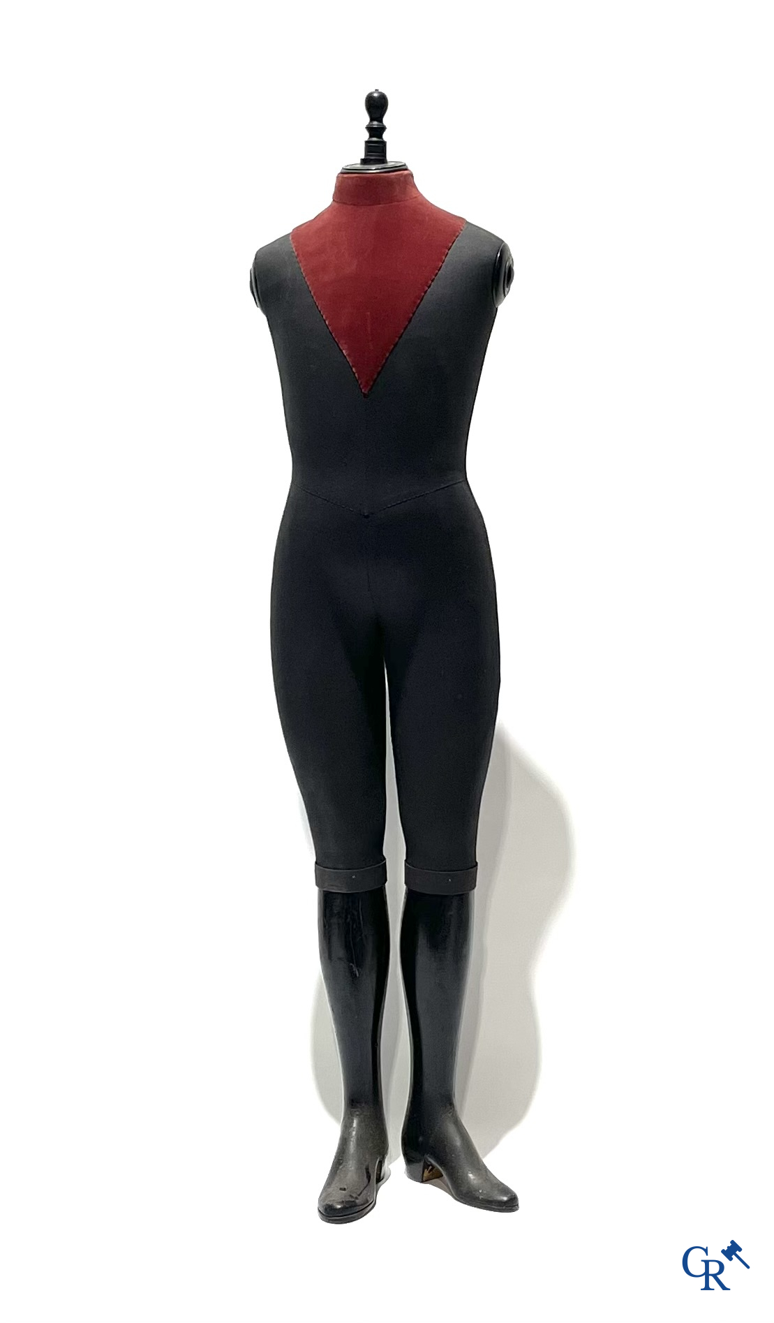 Een kindermannequin met houten laarzen en zwarte stof in de stijl van Stockman. Circa 1900.