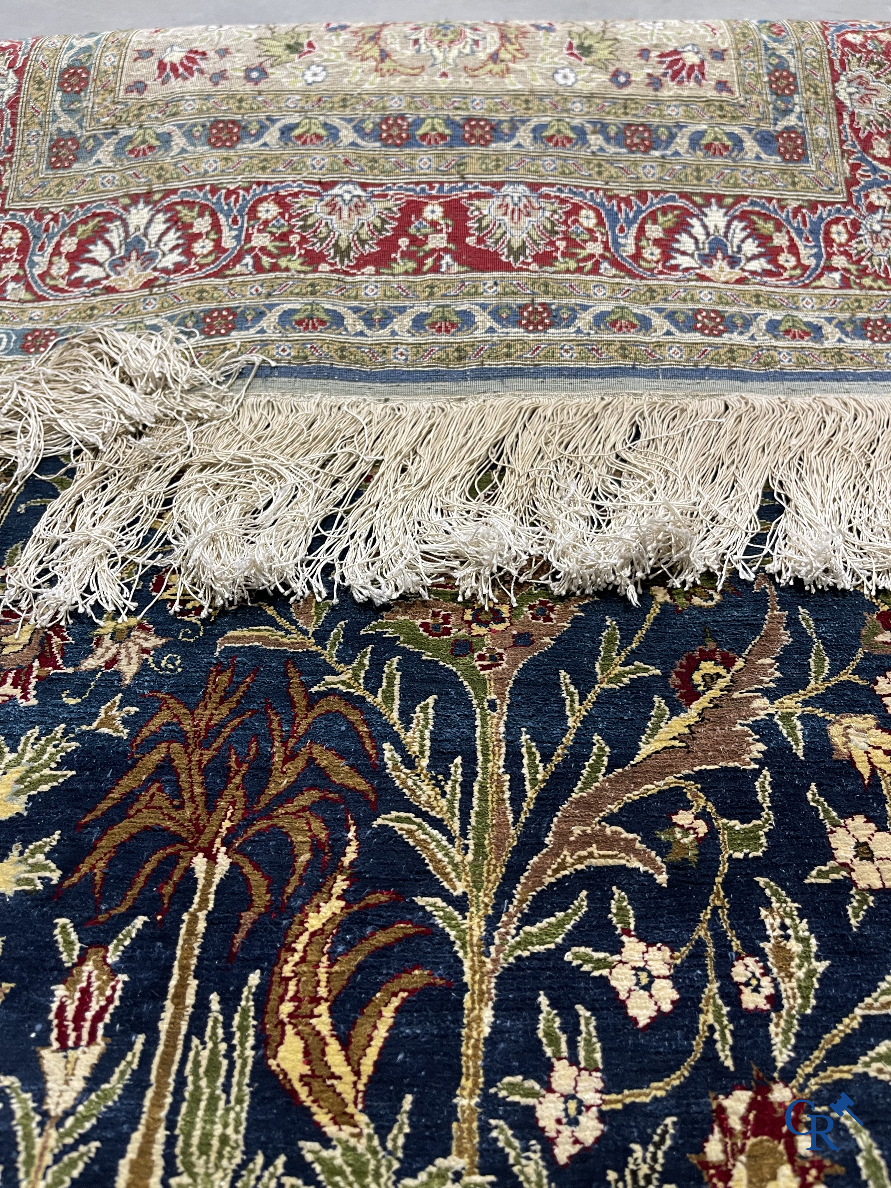 Oosterse tapijten. Een uiterst fijn geknoopt zijden tapijt met floraal decor op donker blauwe achtergrond en gouddraad.