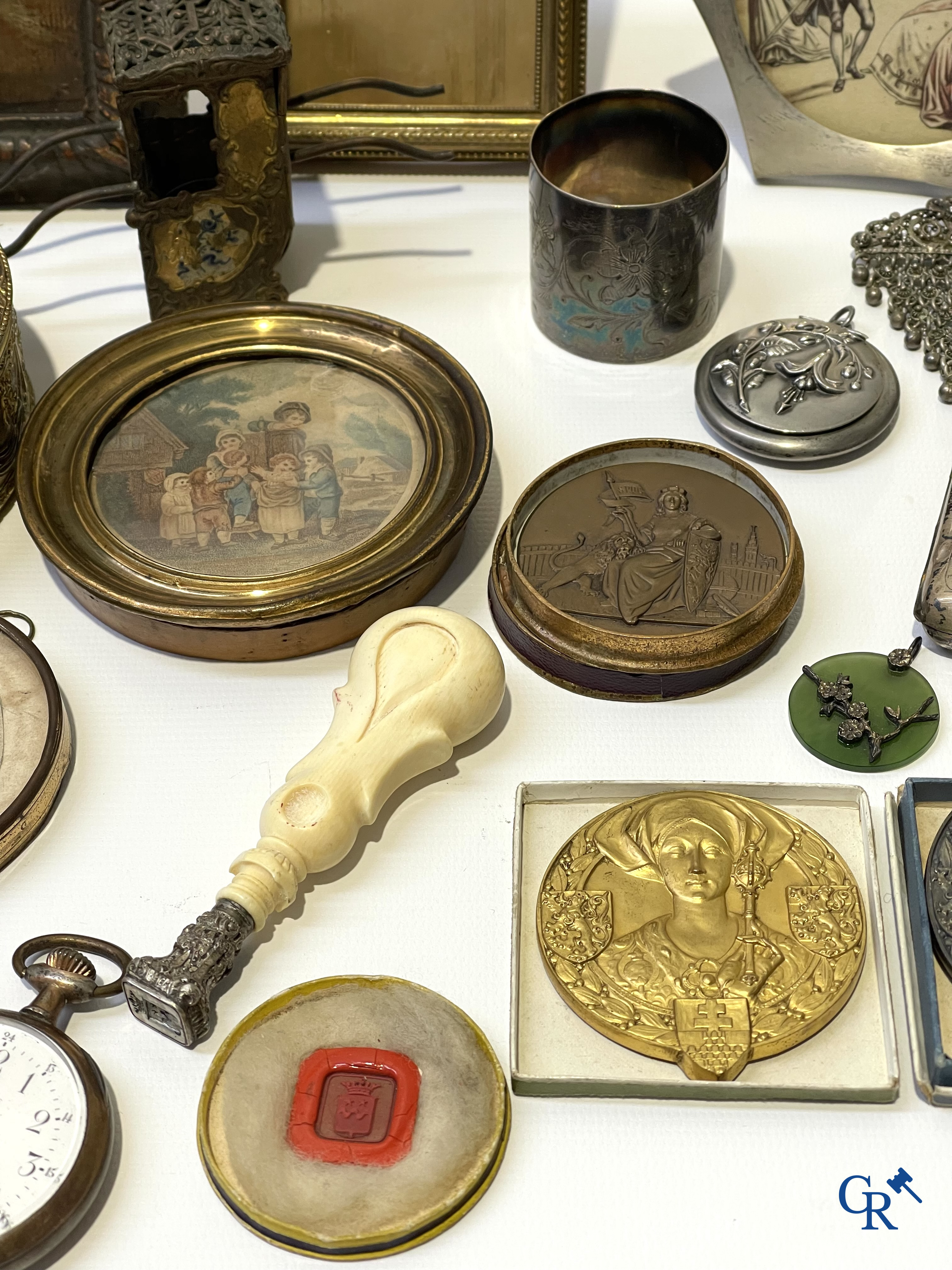 Een uitgebreid lot met vitrineobjecten. Zakhorloges, miniaturen, bronzen kaders, fantasiejuwelen enz. Sommige in zilver.