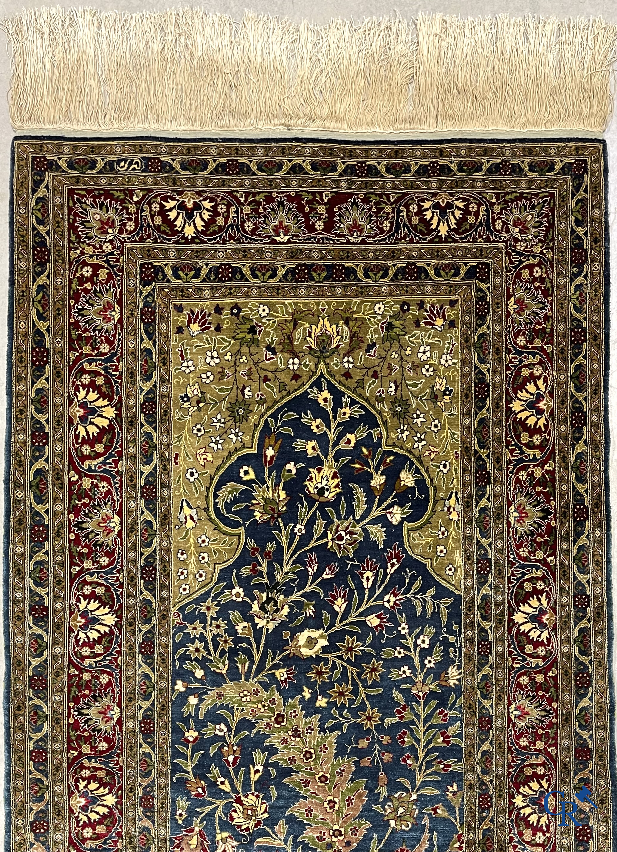 Oosterse tapijten. Een uiterst fijn geknoopt zijden tapijt met floraal decor op donker blauwe achtergrond en gouddraad.