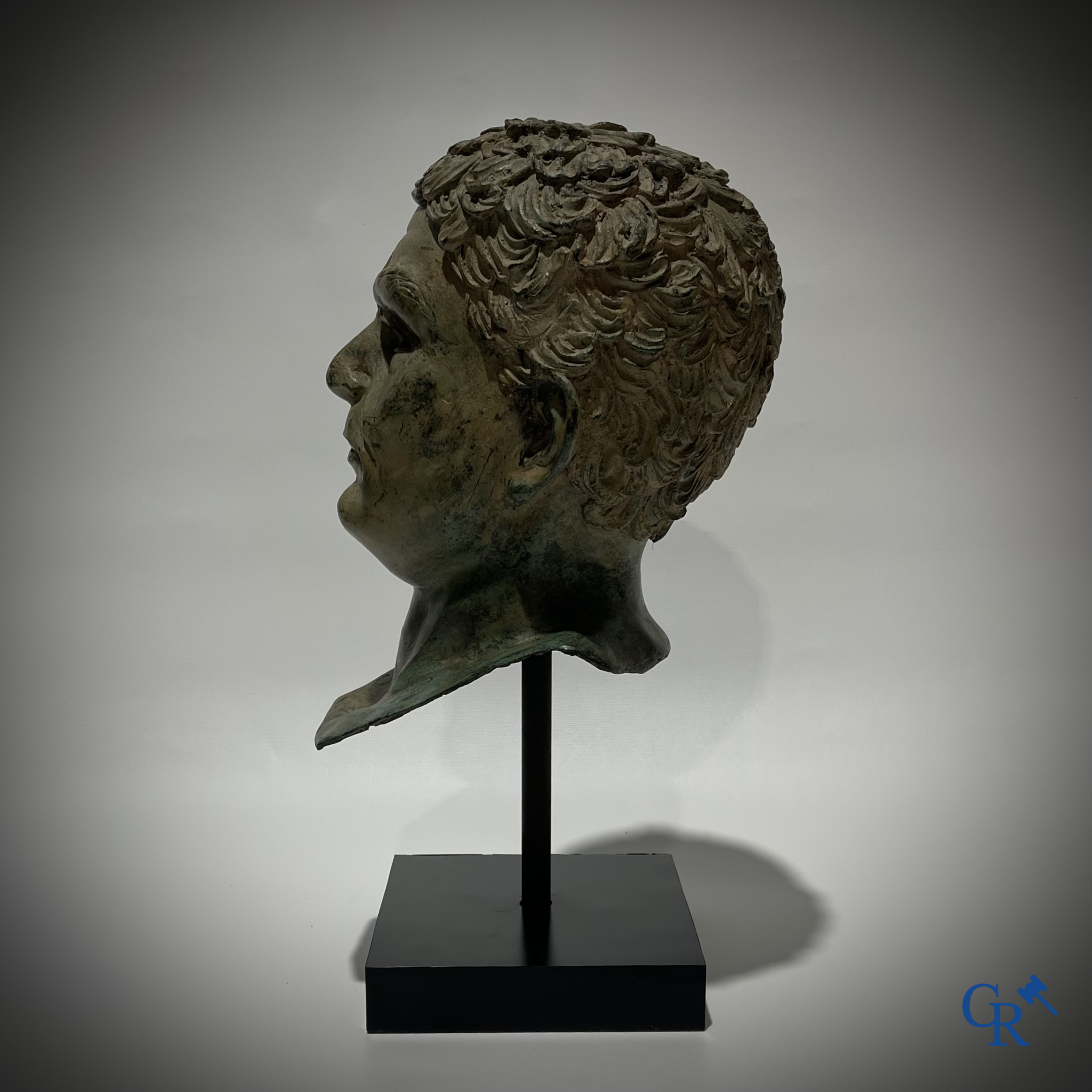 Een bronzen hoofd naar de antieke stijl gemonteerd op een sokkel.