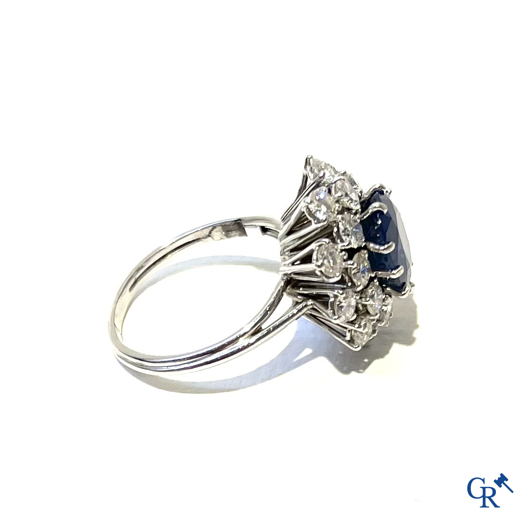 Juwelen. Ring in witgoud 750°/00 bezet met een centrale blauwe saffier omringd door 20 kleine diamanten.