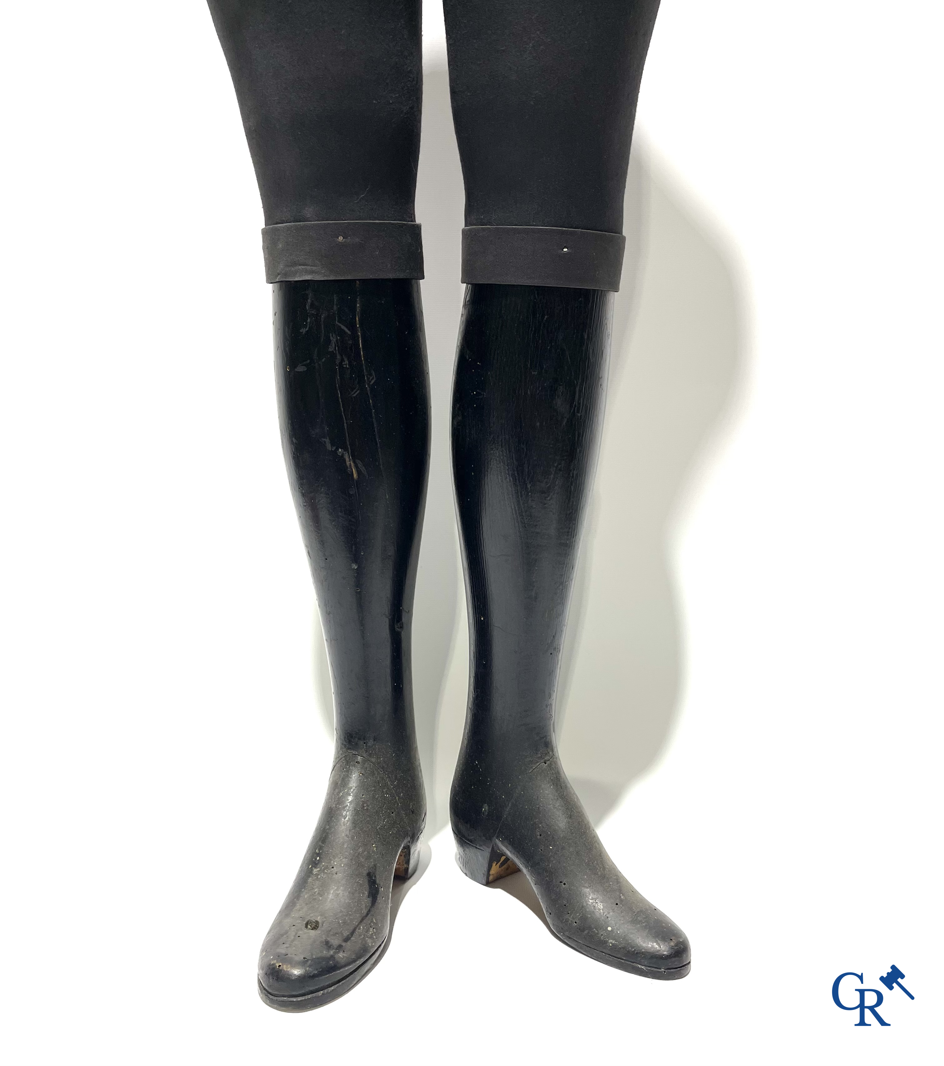 Een kindermannequin met houten laarzen en zwarte stof in de stijl van Stockman. Circa 1900.