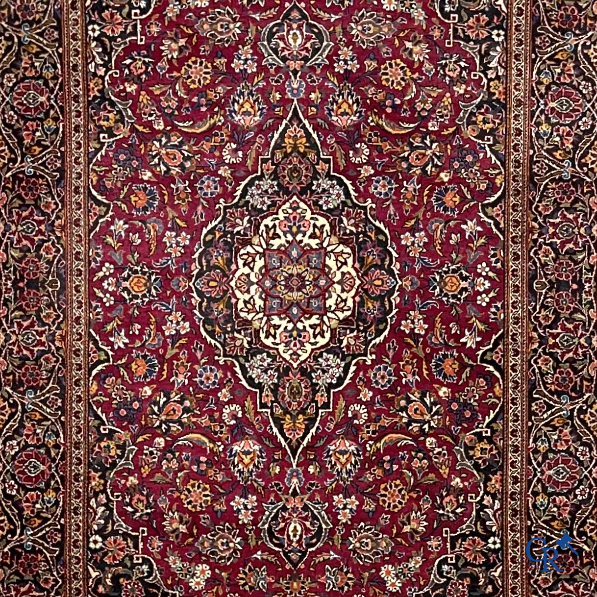 Oosterse tapijten. Een handgeknoopt oosters tapijt met floraal decor op rode achtergrond.