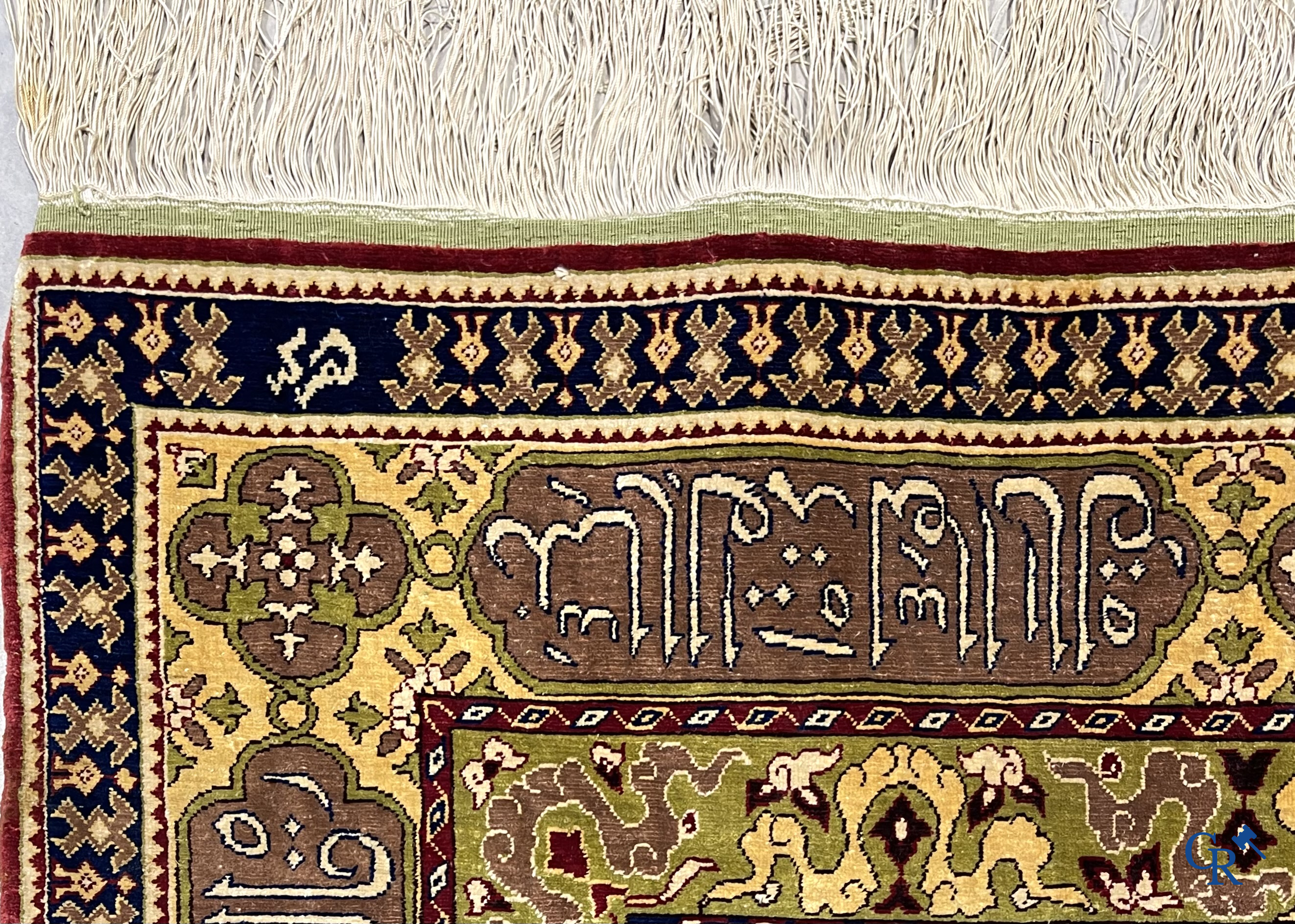 Oosterse tapijten. Een uiterst fijn handgeknoopt zijden tapijt met inscripties en gouddraad. Gesigneerd.