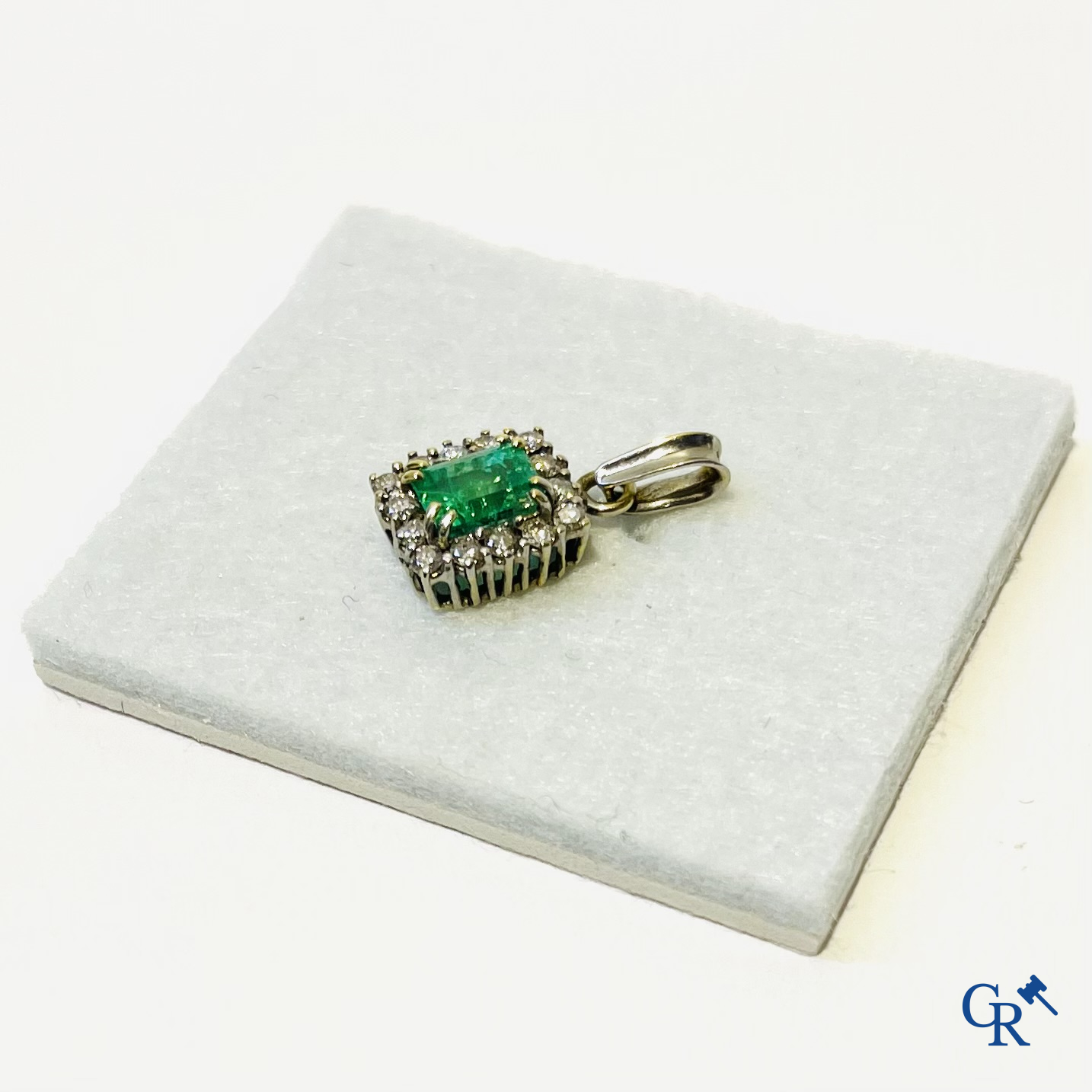 Juwelen. Een platina ring met smaragd en diamanten en een hanger in witgoud 750°/00 met smaragd en 14 diamanten.