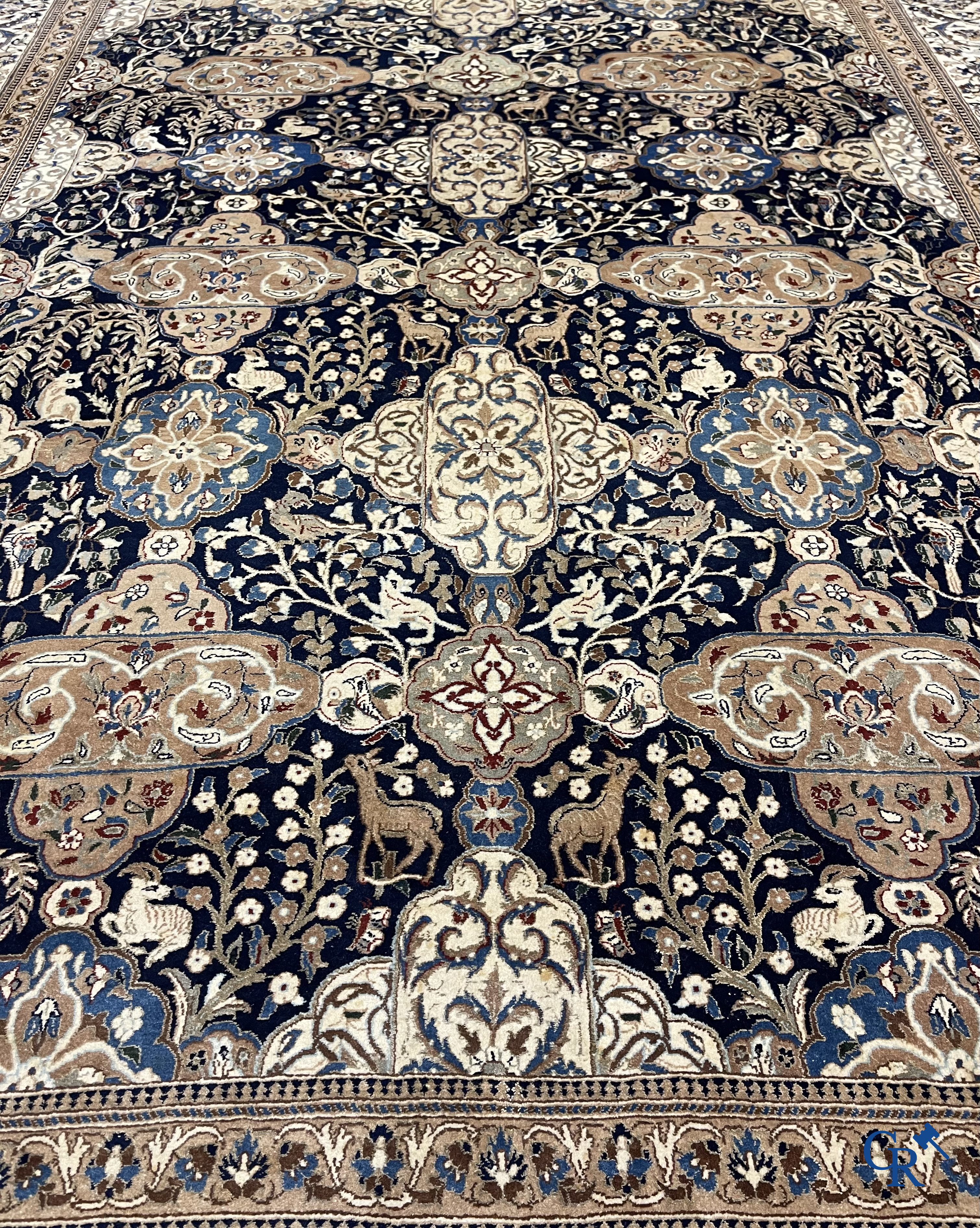 Oosterse tapijten. Een handgeknoopt tapijt met wouddieren en bloemen.