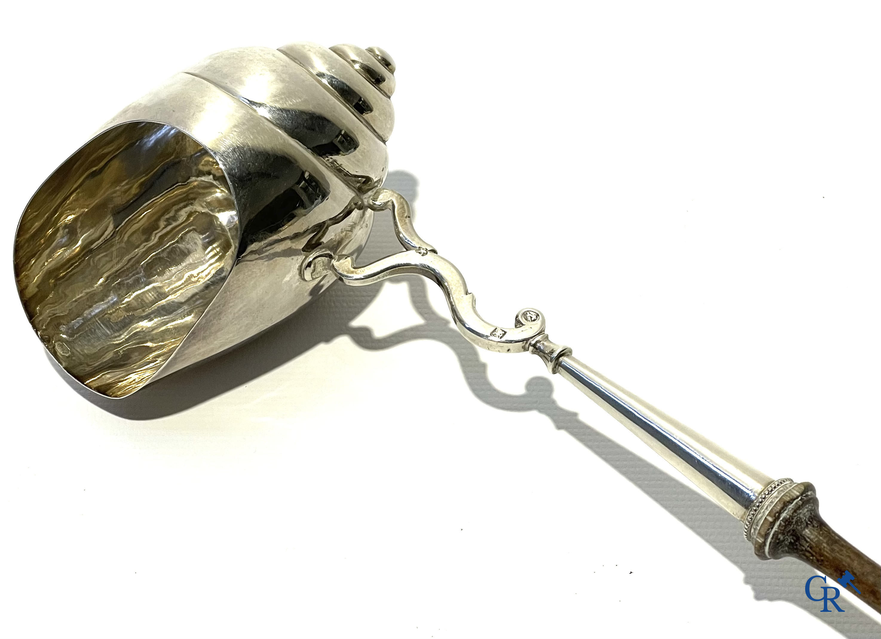 Zilveren punchlepel in de vorm van een slakkenhuis met houten steel.  Zilver 1ste gehalte. Meerdere keurmerken.