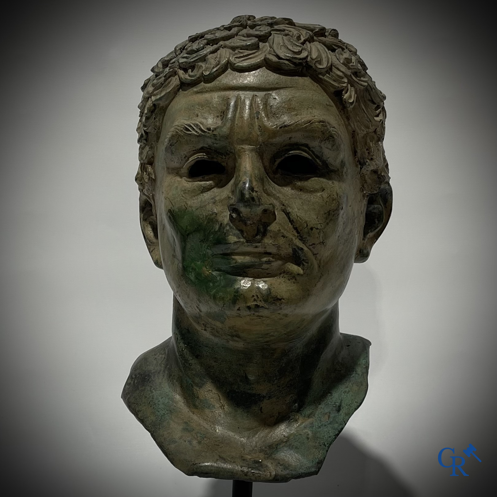 Een bronzen hoofd naar de antieke stijl gemonteerd op een sokkel.