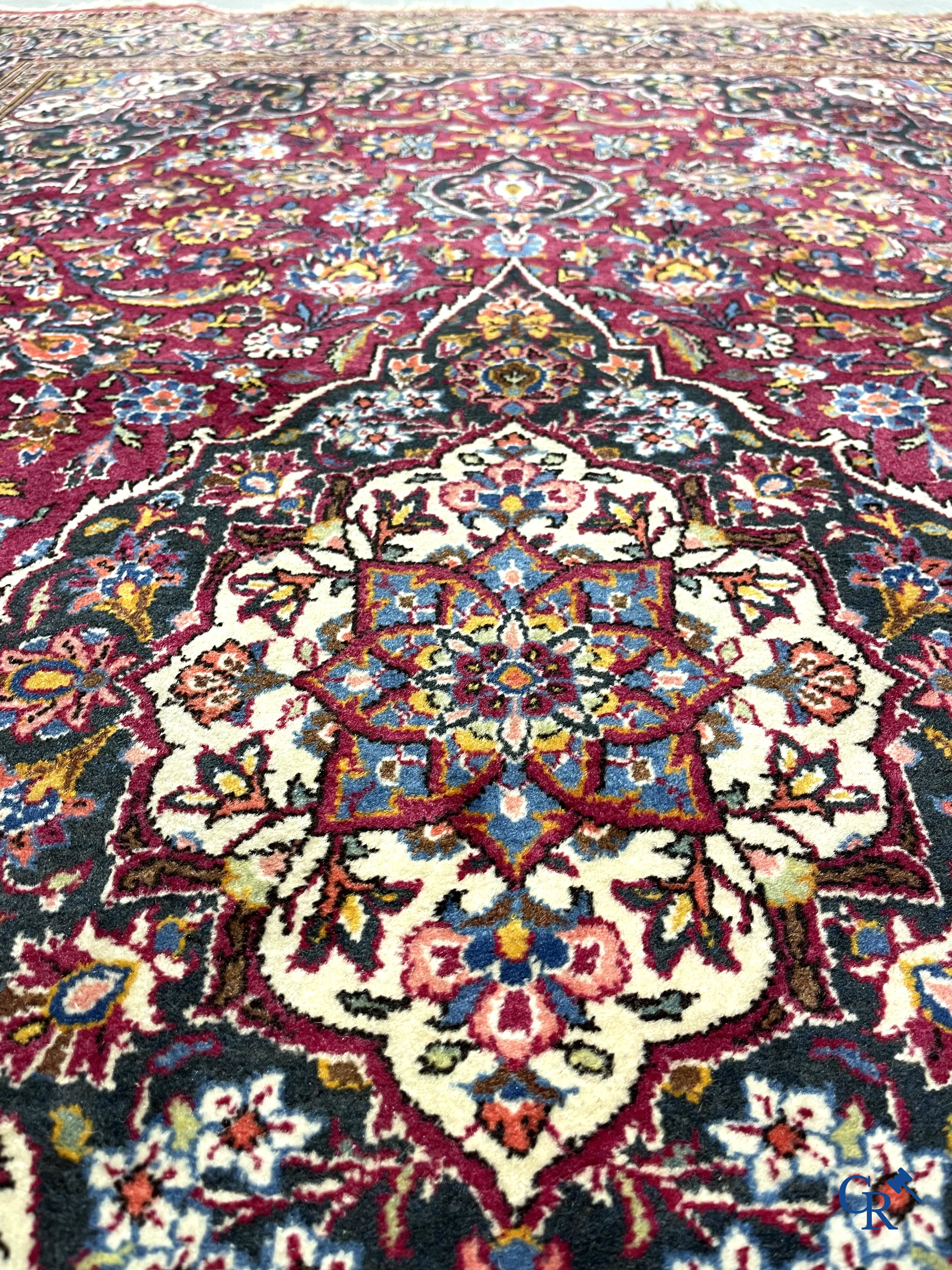 Oosterse tapijten. Een handgeknoopt oosters tapijt met floraal decor op rode achtergrond.