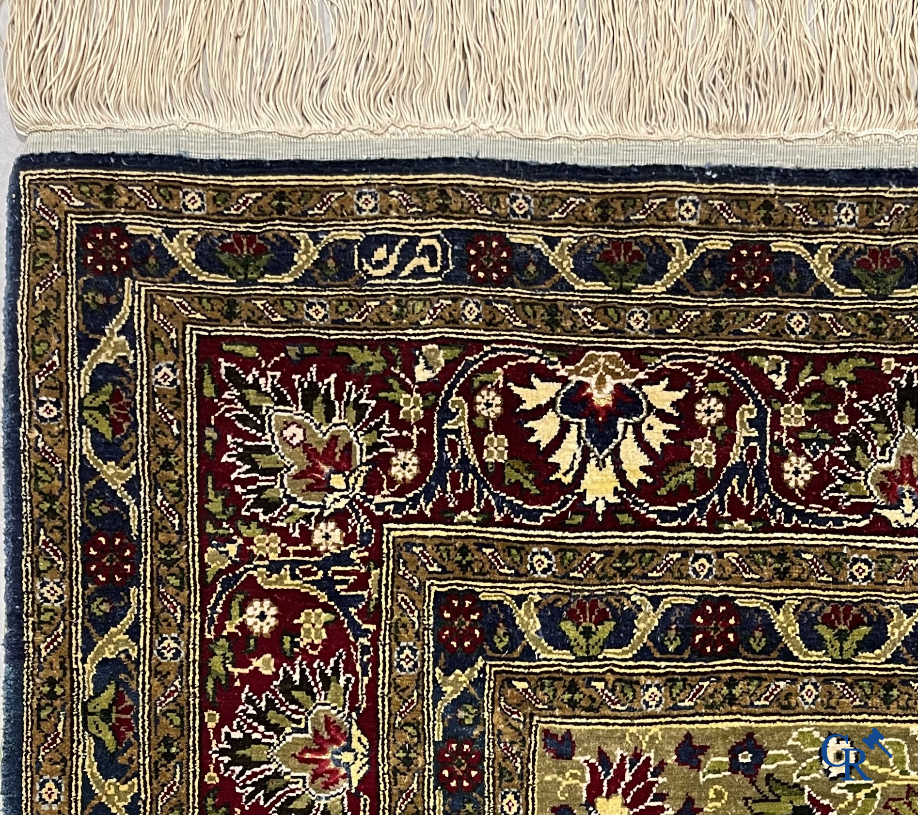 Oosterse tapijten. Een uiterst fijn geknoopt zijden tapijt met floraal decor op donker blauwe achtergrond en gouddraad.