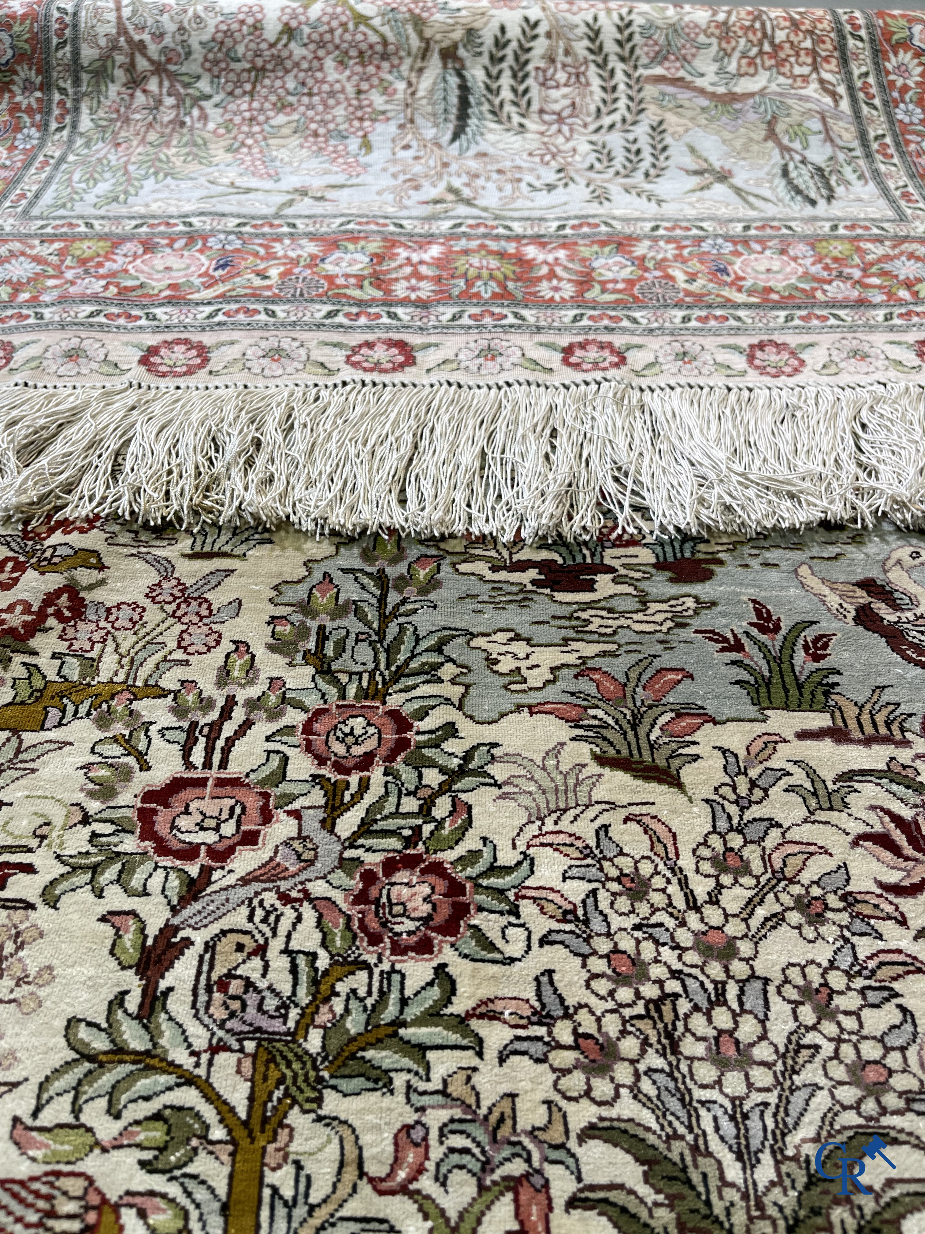 Oriental carpets: A finely hand-knotted silk carpet with water birds in a landscape on a floral background.