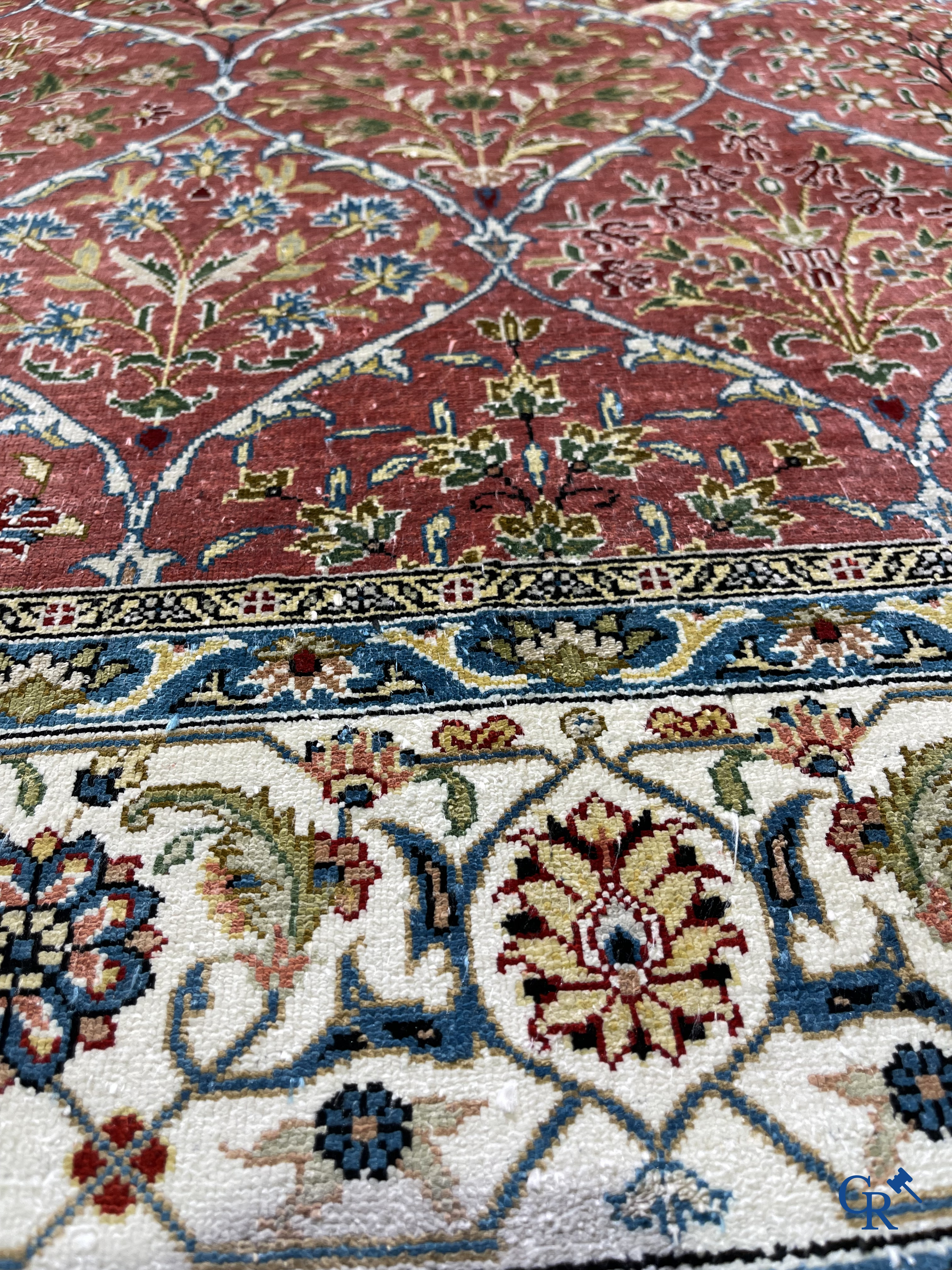 Tapis d'Orient: Un tapis finement noué à la main en laine et soie avec un décor floral.<br />
Signé.