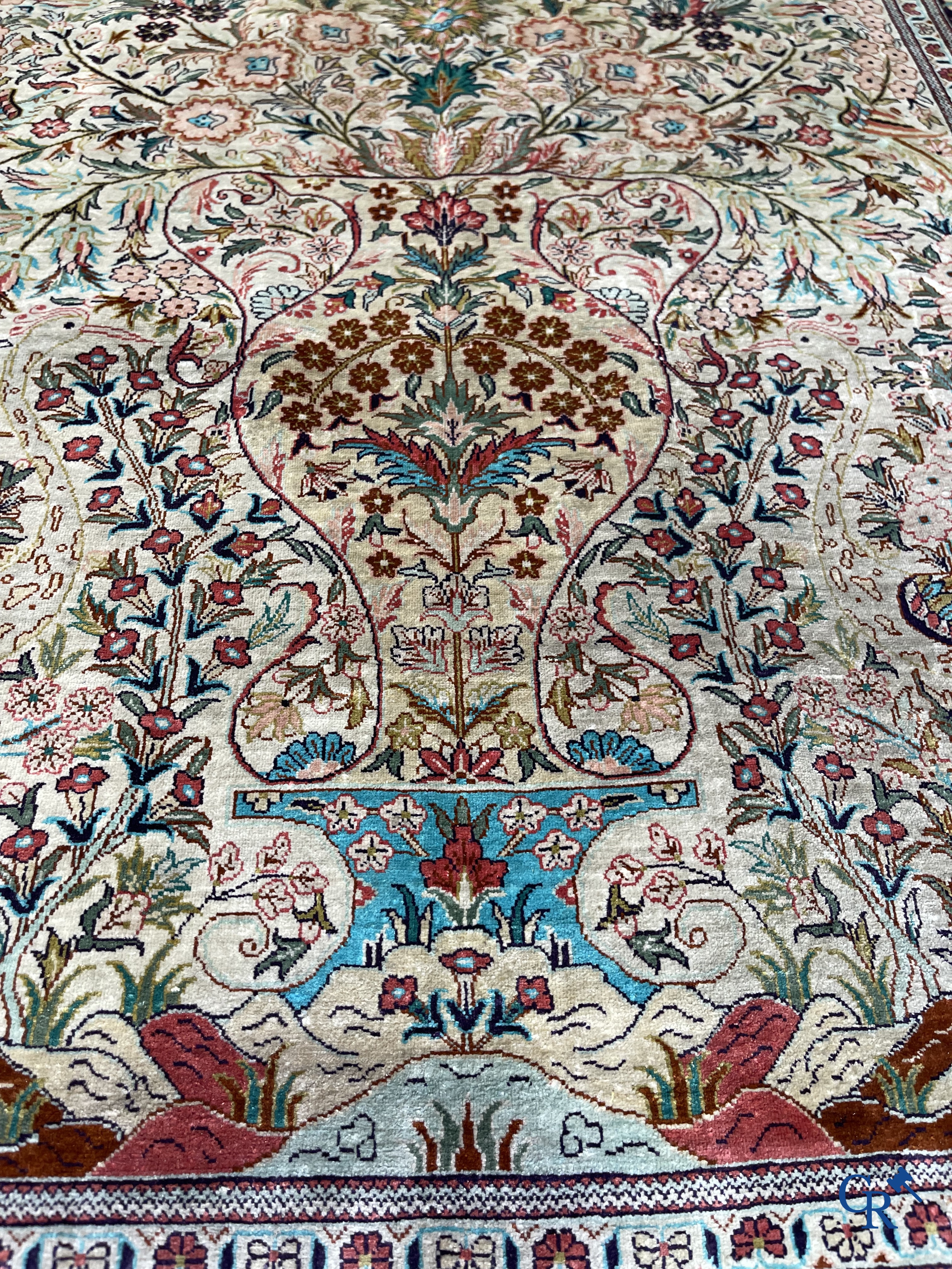 Tapis d'Orient: Un tapis persan en soie finement noué à la main avec un vase à fleurs et des oiseaux dans un décor floral.