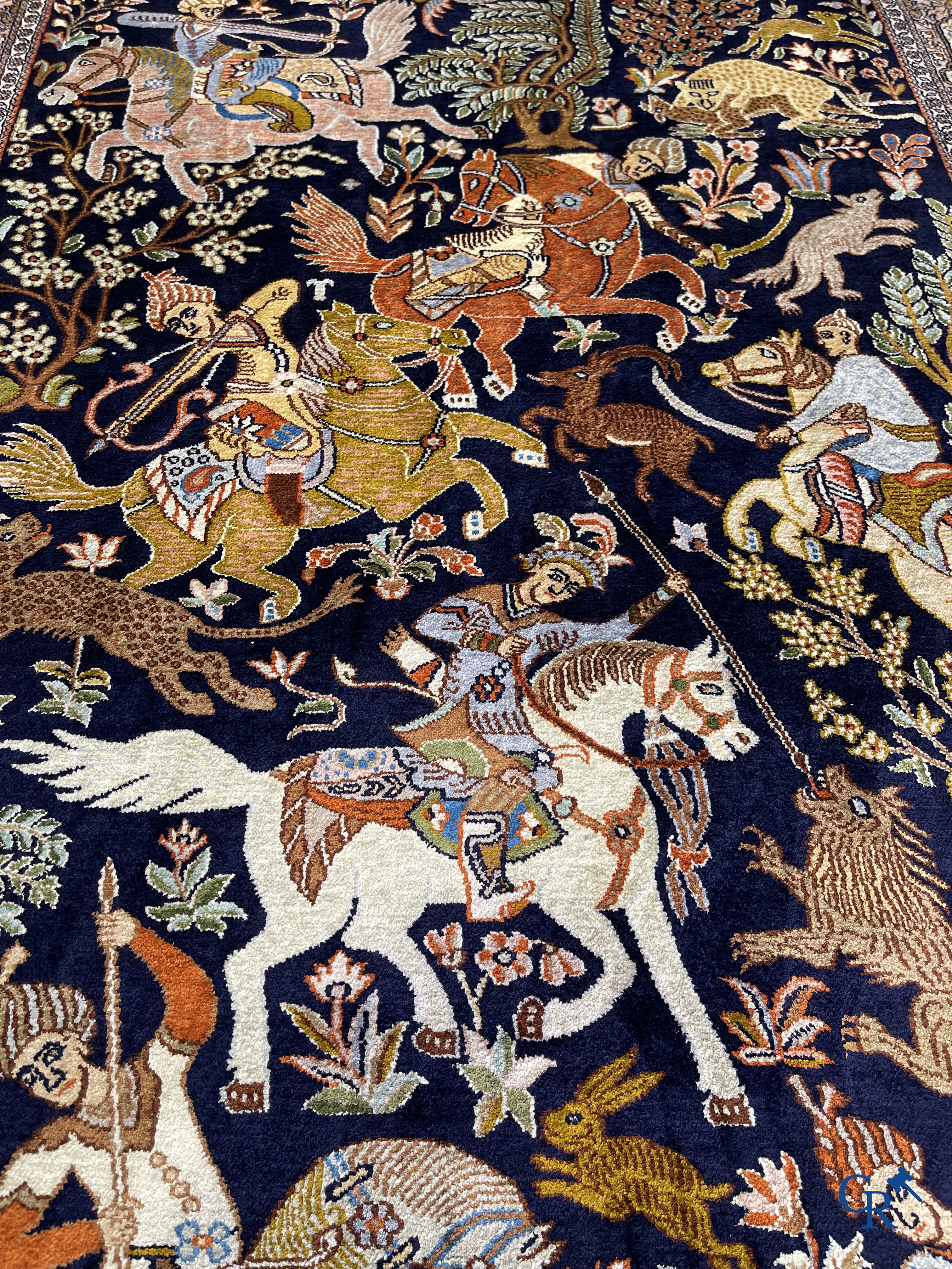 Oriental rugs. Iran. A finely hand-knotted Persian rug in wool and silk with hunters on horseback and inscriptions.