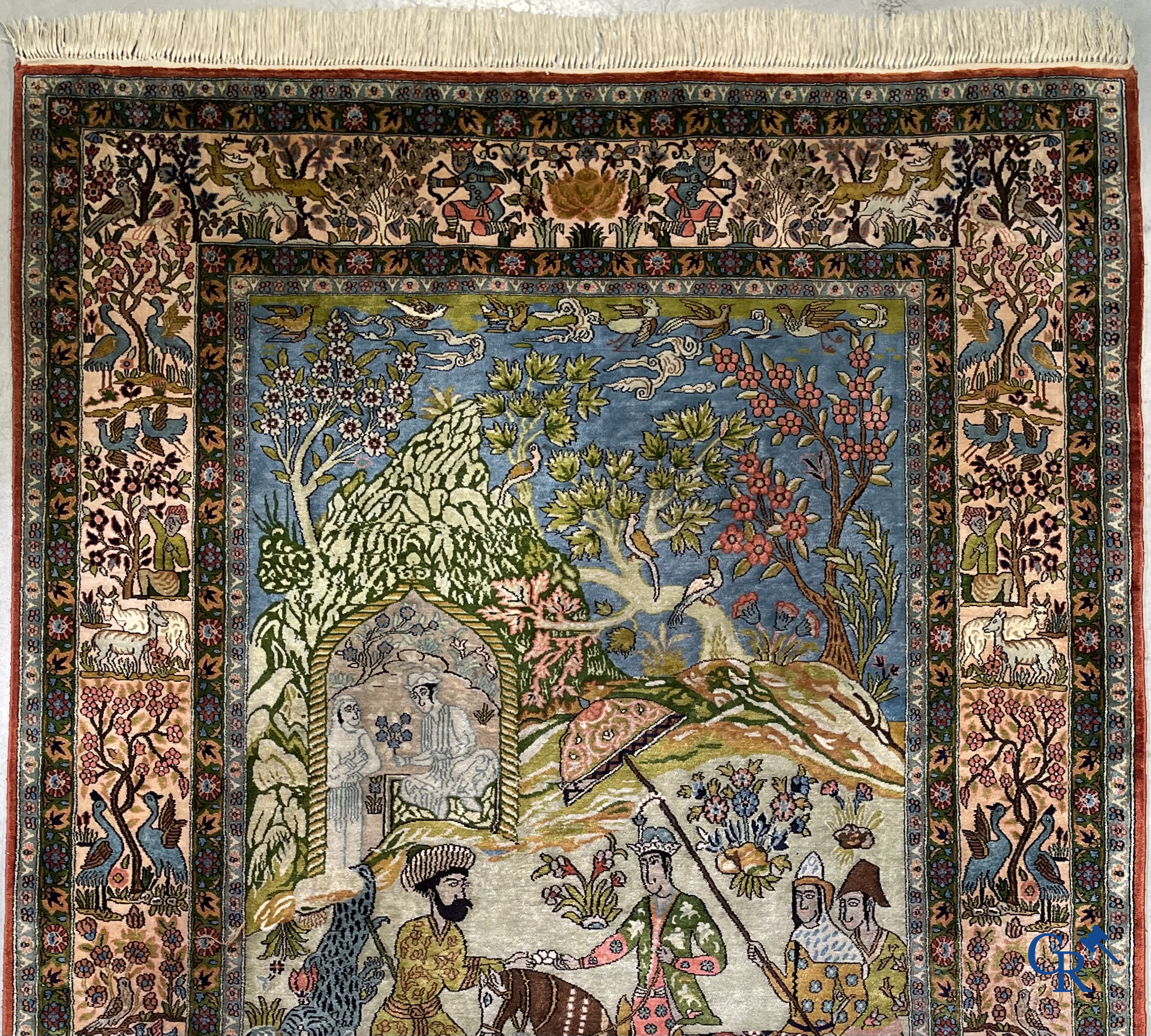 Tapis d'Orient. Iran. Un tapis persan en soie finement noué à la main avec des personnages et un cheval dans un paysage.